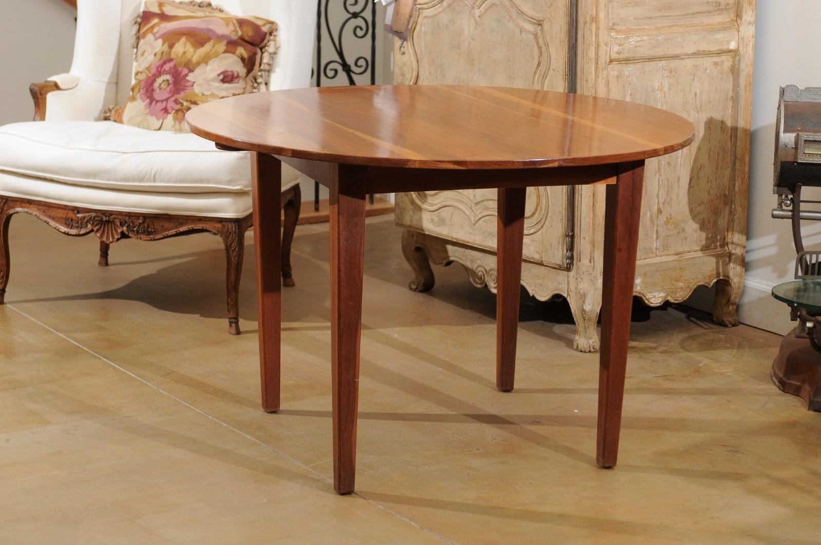 An American round cherry dining table from the 20th century, with tapered legs and square apron. Simple yet elegant, this American cherry dining table charms us with its pure lines and lovely finish. A two-toned circular top sits on a square apron