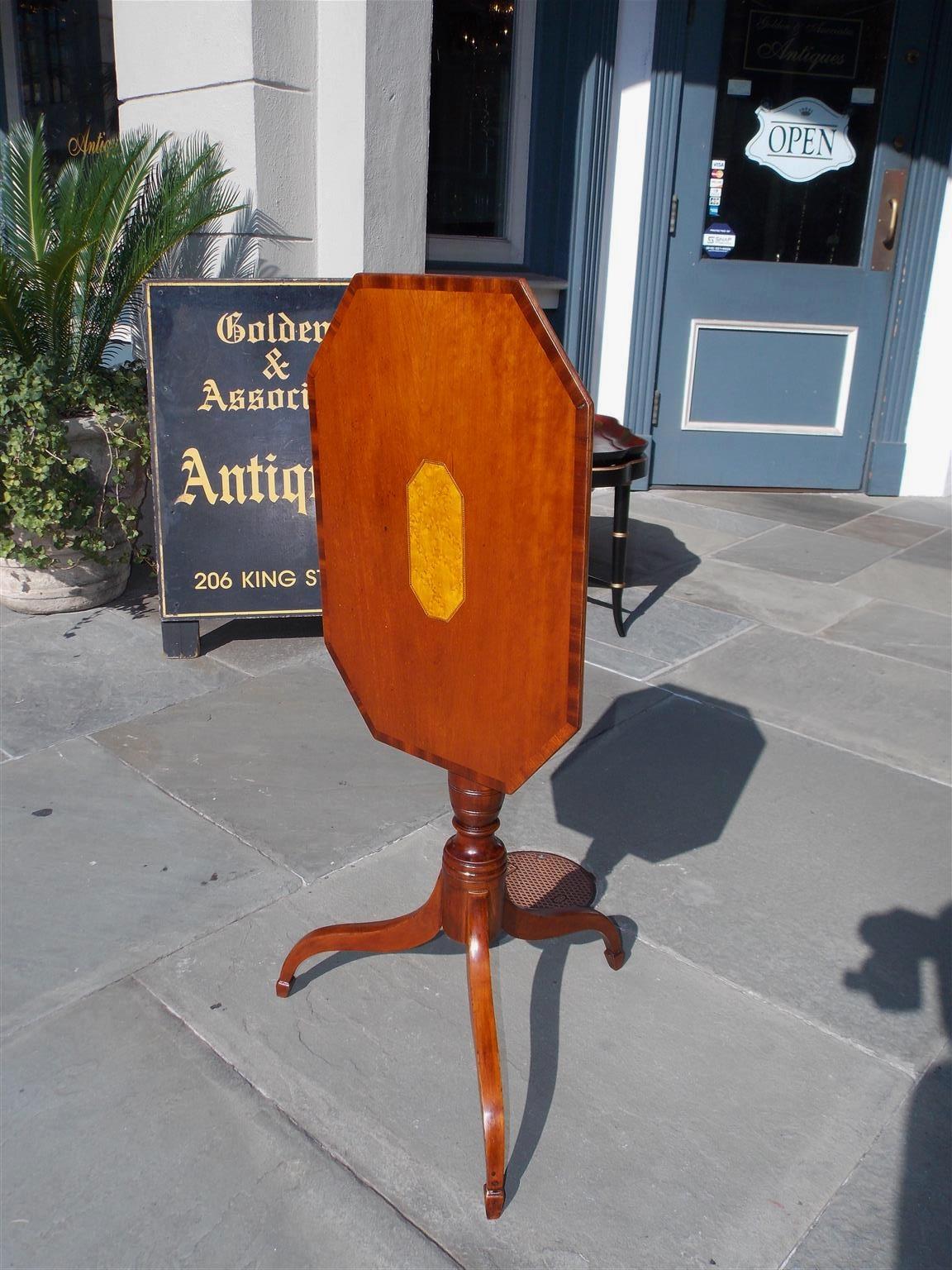 American cherry tilt-top octagon candlestand with mahogany edged cross banding, centered bird’s-eye maple inlay, original brass locking mechanism, bulbous turned ringed pedestal, and resting on splayed tripod legs with spade feet, early 19th century.