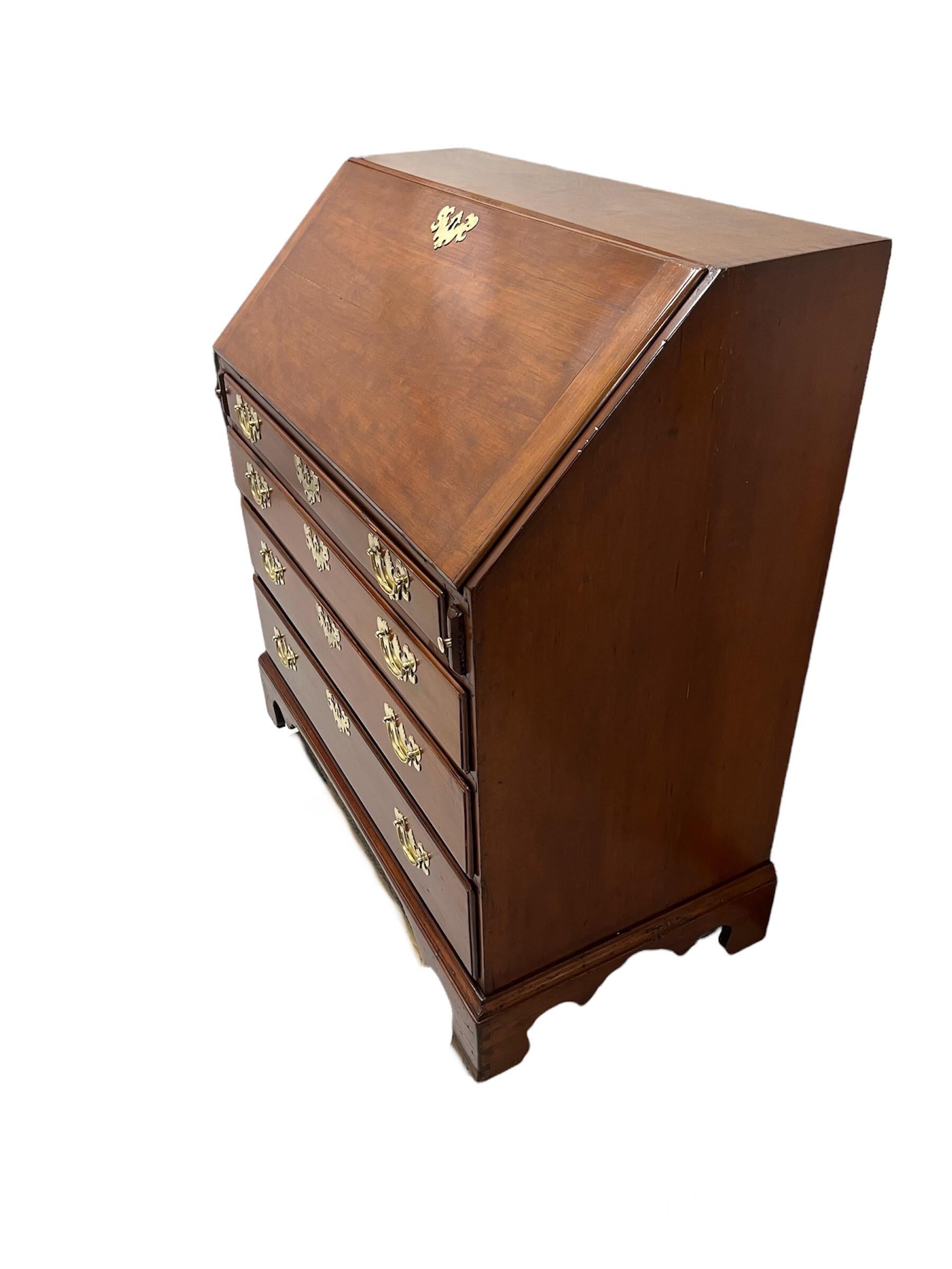 American Cherry Wood Slant front Desk  with fitted interior with a center door flanked by pigeon hole compartments above four graduated drawers. Raised on bracket feet. With brass handles,back plates & Keyhole discussions.