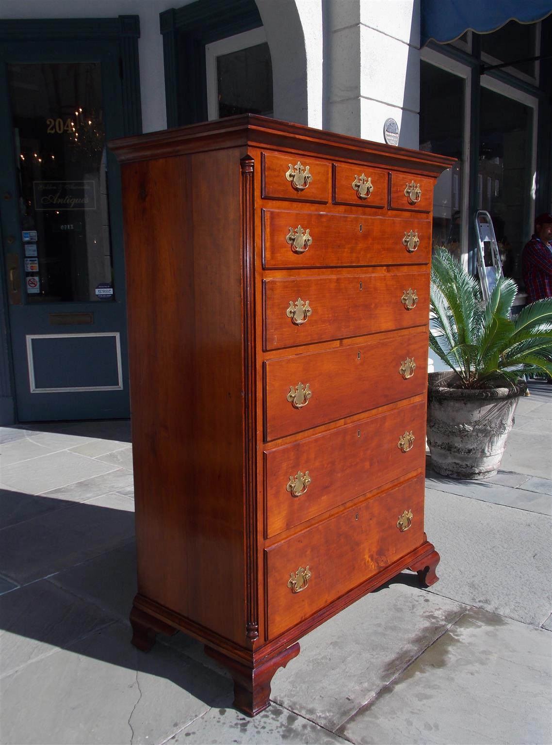 American Chippendale cherry tall chest of drawers with a carved molded edge cornice, flanking fluted quarter columns , three upper drawers over five graduated drawers with period brasses, and terminating on a carved molded edge base with the