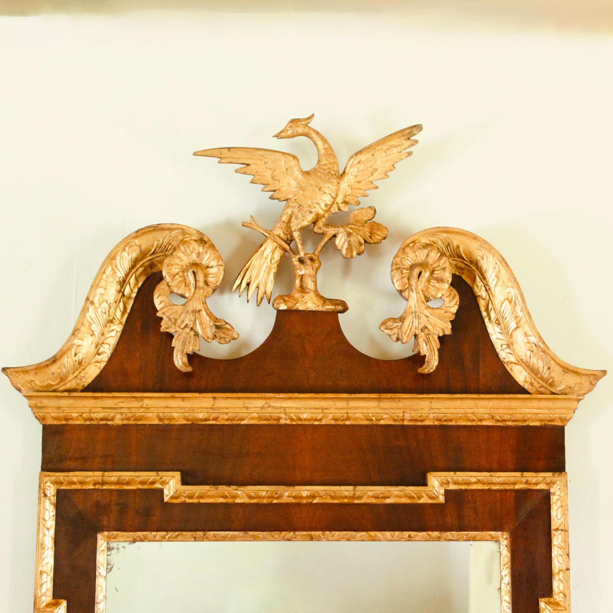 A fine ca. 1780’s American Chippendale Federal wall mirror with a scrolling “broken pediment” which flanks a central pedestal holding a Ho Ho bird with outstretched wings standing on a branch springing from a bit of rockery. The pediment is nicely