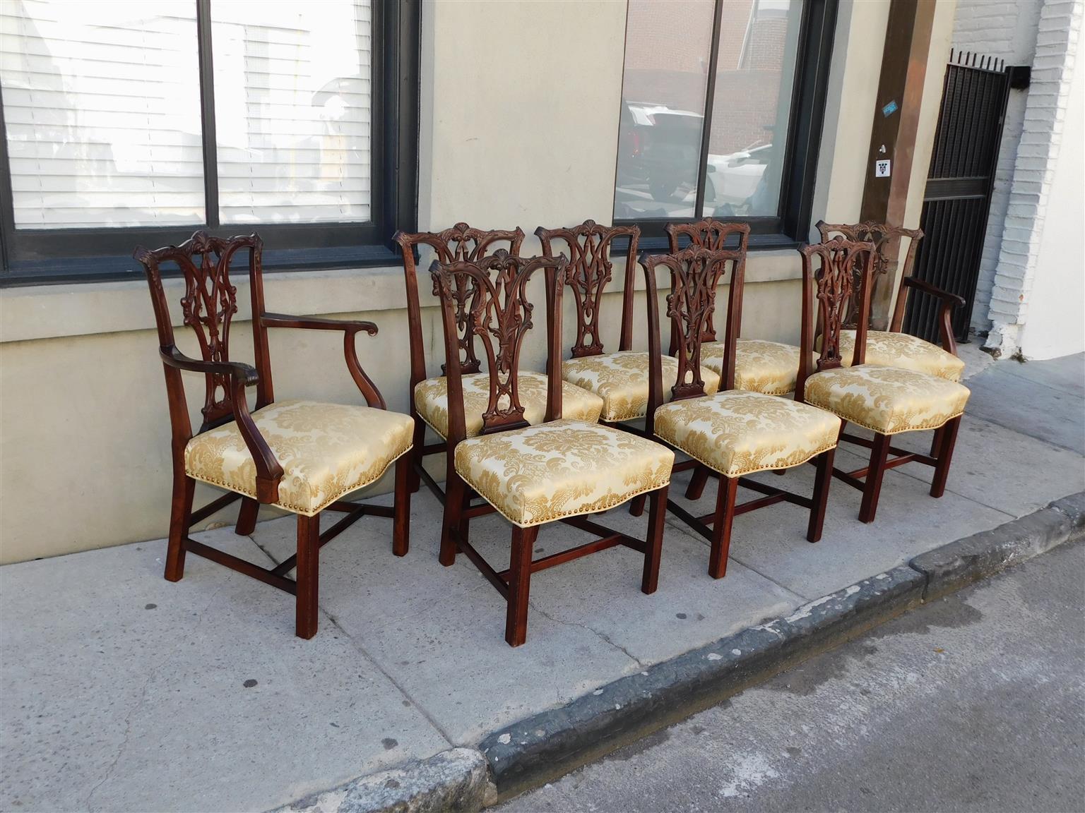 Set of Eight American Mahogany Chippendale serpentine form carved acanthus foliage dining room chairs with intertwined foliage splat backs,  upholstered foliage tacked seats, frontal straight legs, rear splayed legs, and original connecting