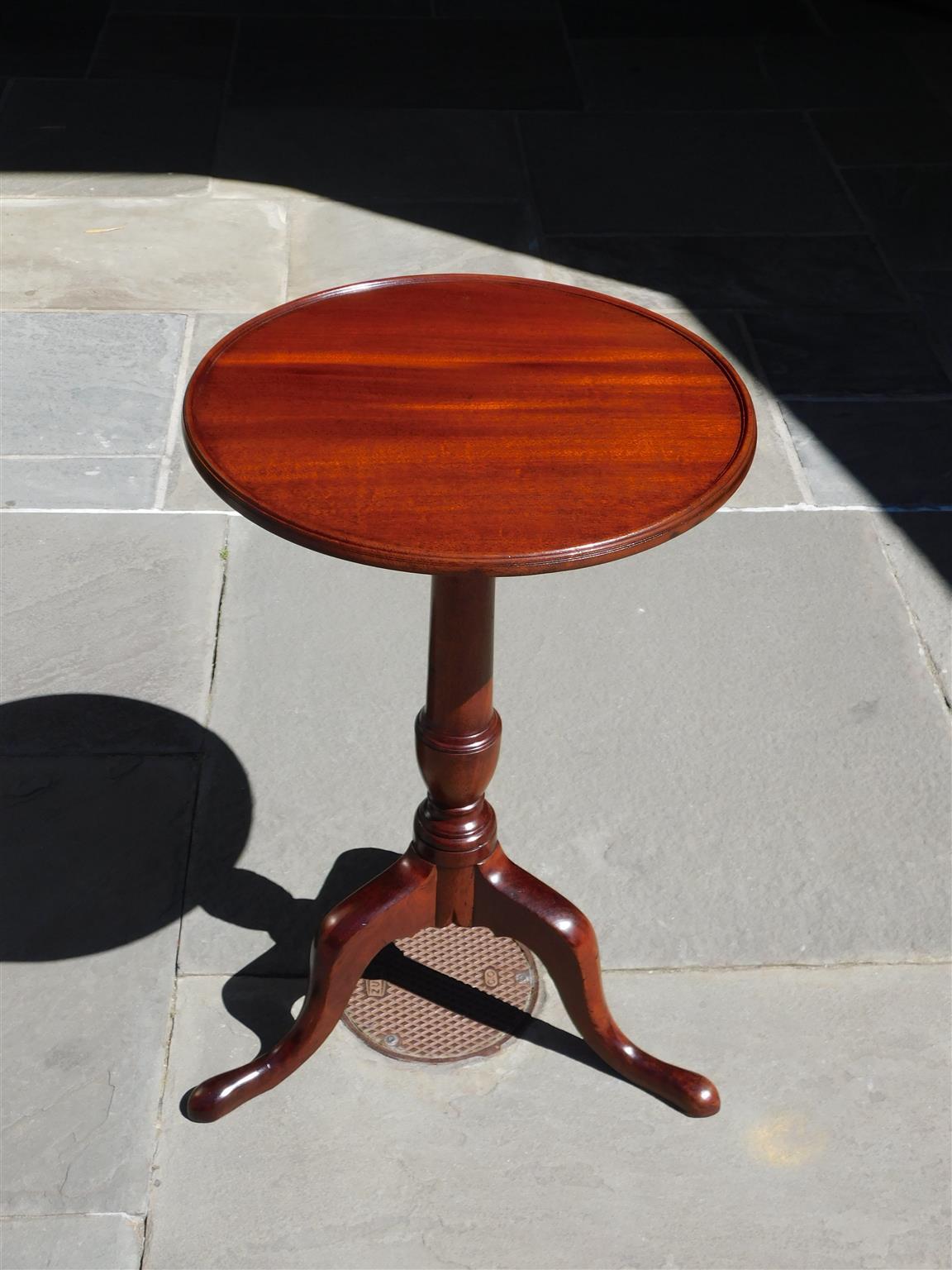 American Chippendale mahogany tilt top kettle stand with a circular molded dish top, rotating birdcage, original brass locking mechanism, carved bulbous urn ringed pedestal, and resting on carved knees with slipper feet. Mid-18th Century.