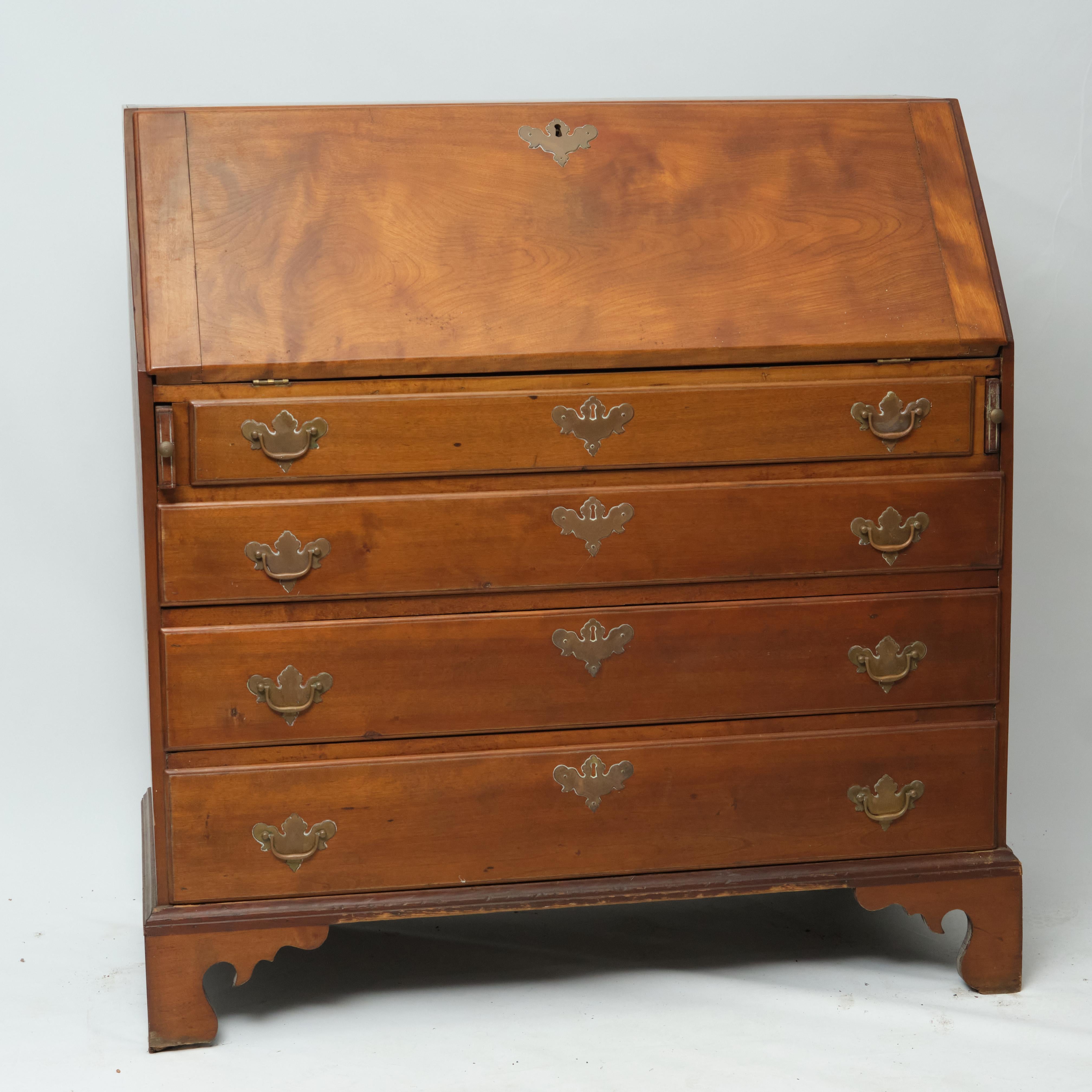Late 18th/early 19th century American Chippendale slant-front desk in maple. Slant front with lock opens to fitted interior, having two central drawers with carved rosettes. Over four drawers with brass pulls. None of the drawers are locking. Raised