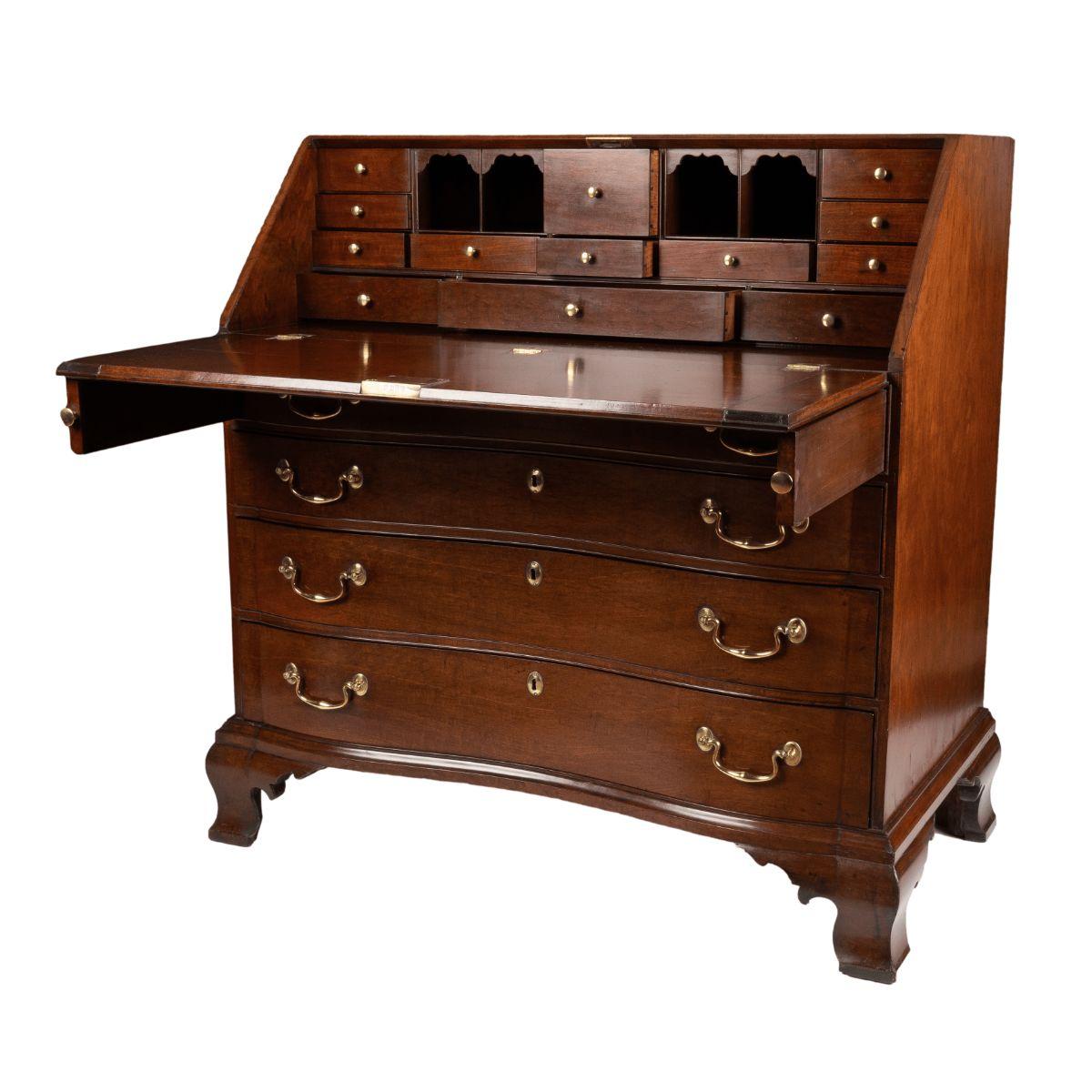 Bureau américain de style Chippendale à façade inclinée reposant sur quatre tiroirs gradués et sur des pieds en console ogée. Les tiroirs en arc de cercle sont bloqués aux angles, ce qui se prolonge dans les pieds en console ogée. Le couvercle du