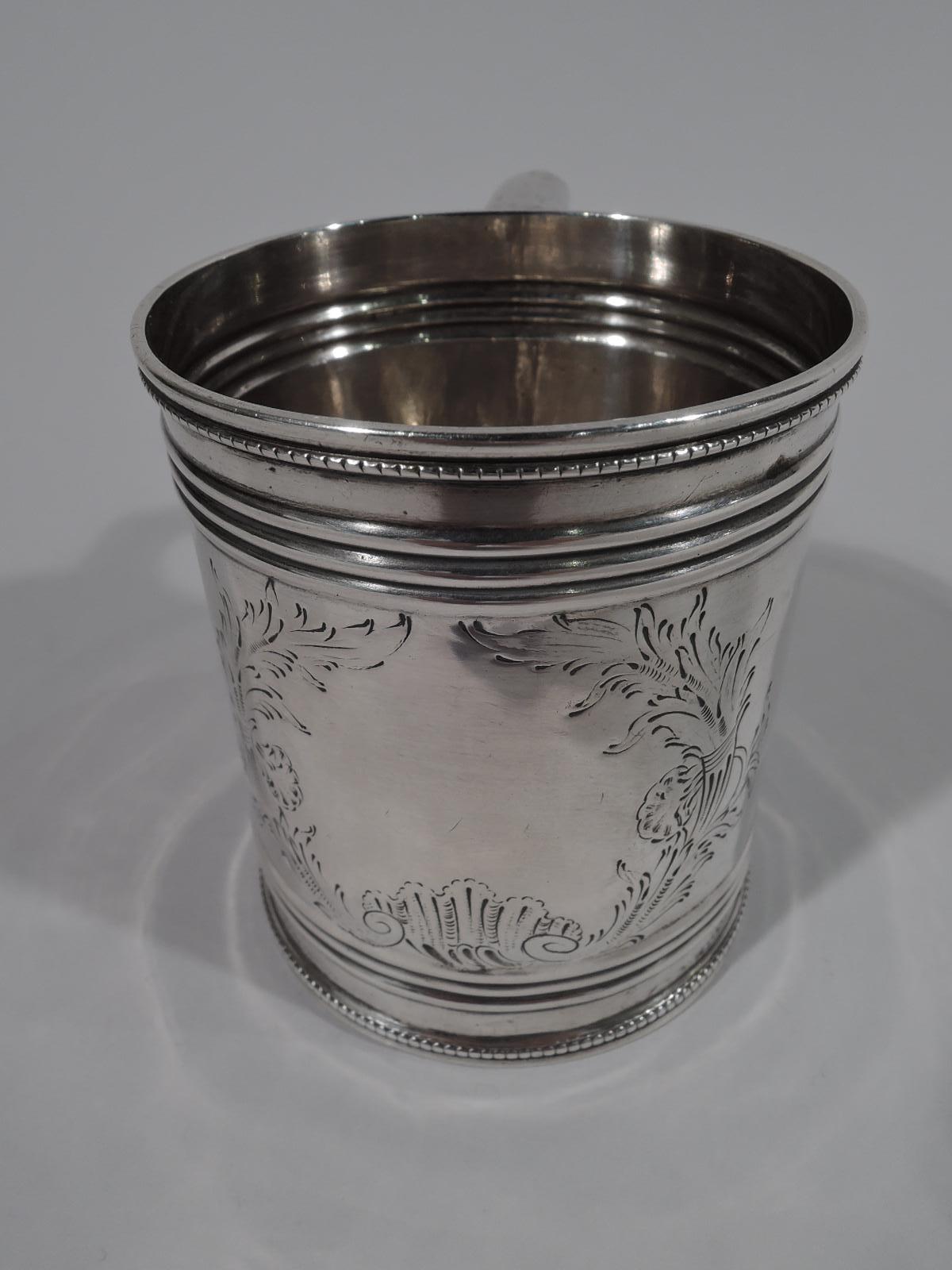 Classical coin silver baby cup, drum-form with ribbing and beading. Engraved quivers, flowers, and leaves forming cartouche (vacant). Scroll-bracket handle. Marked “G. W & H” for Gale, Woods & Hughes, a New York maker active circa 1833-1845. Weight: