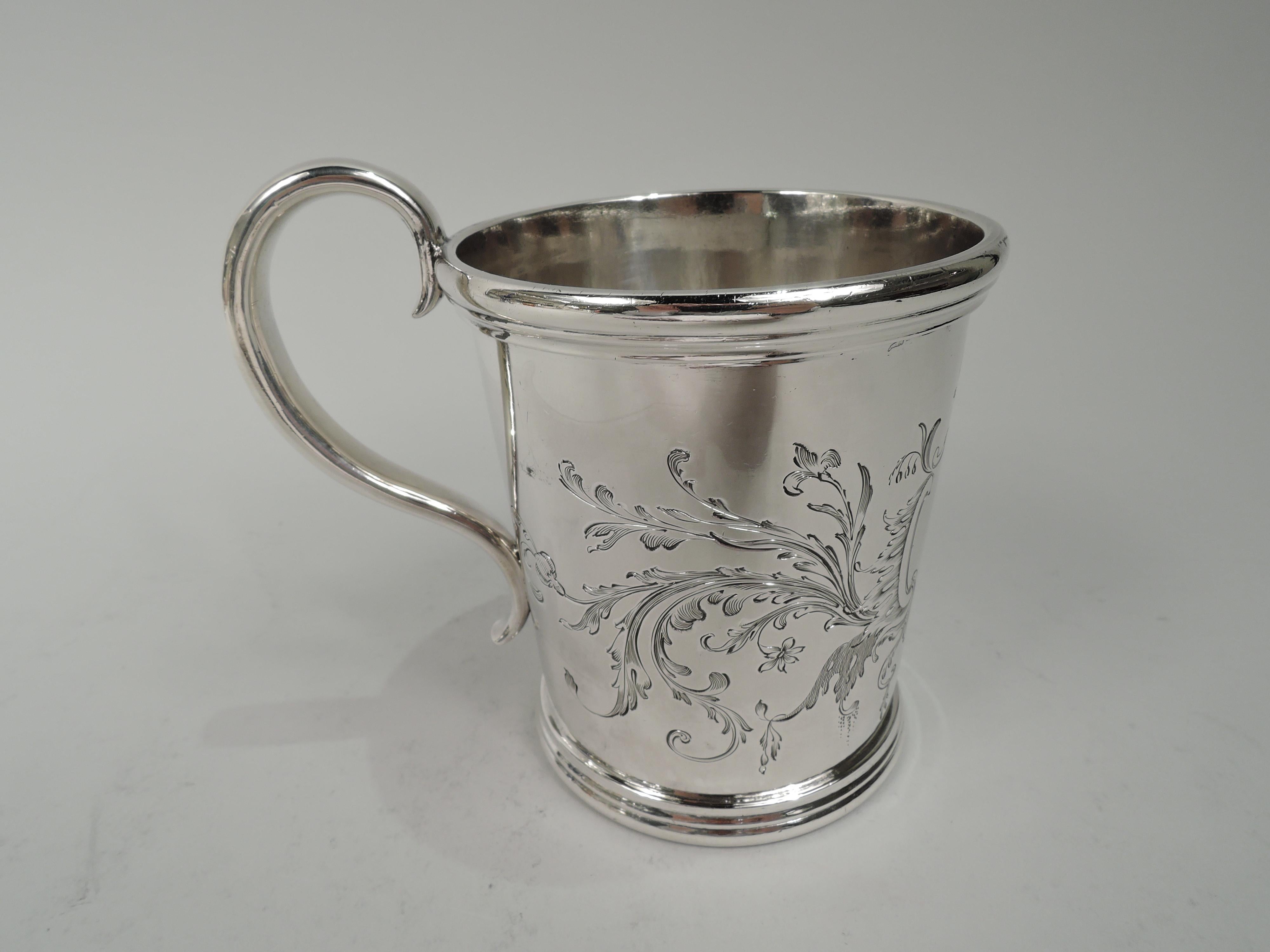 American Classical coin silver baby cup, ca 1840. Retailed by Lincoln & Reed in Boston Gently tapering sides with high-looping s-scroll handle. Reeded rims. Beautifully engraved ornament: scrolled frame (vacant) surrounded by leafing scrolls and