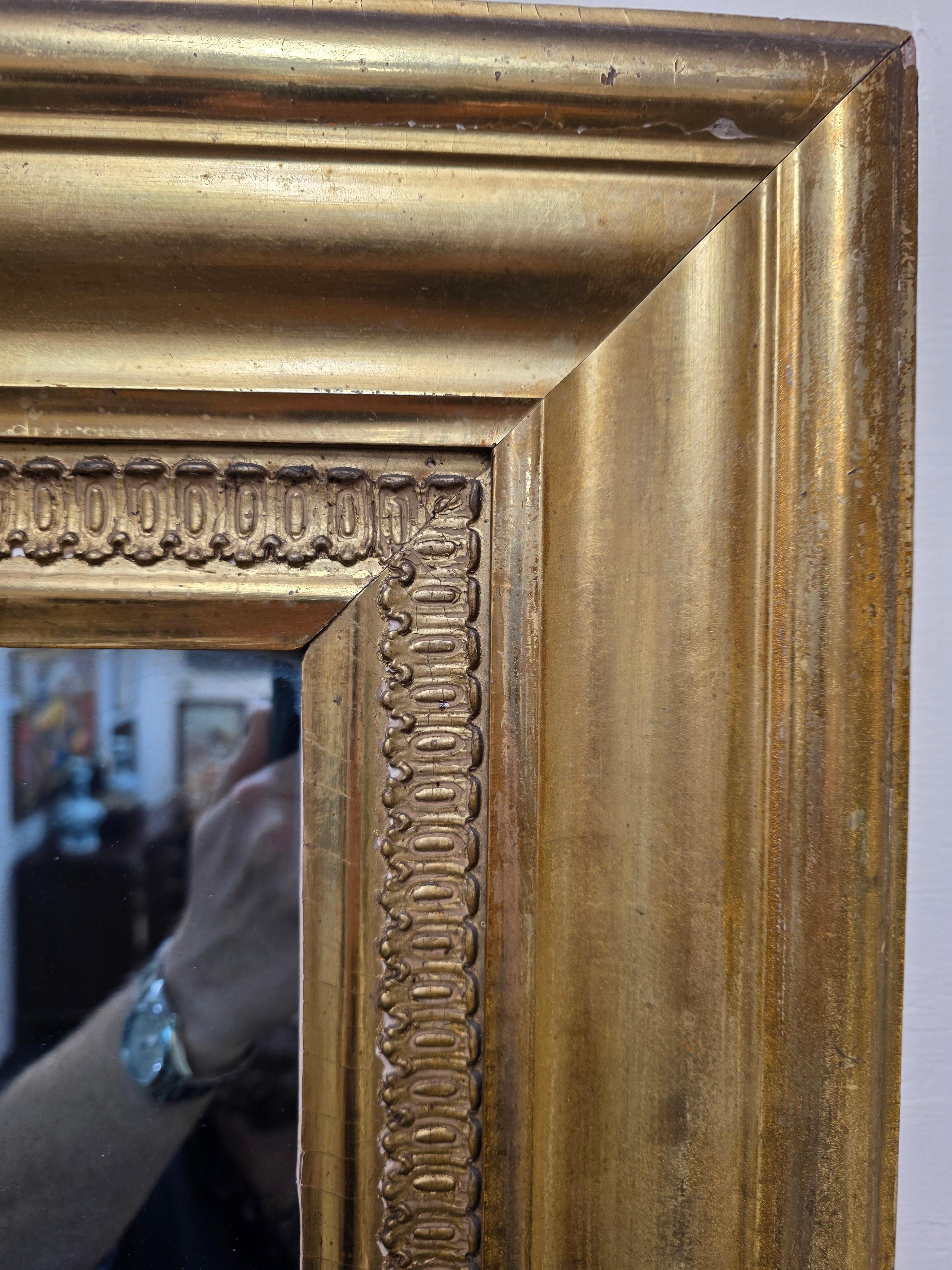 A beautiful, American classical, looking glass made by The Firm of James Burton from Albany New York. This large and beautiful mirror retains the original bluish glass and gilded surface. But most extraordinarily a pair of tags on the back