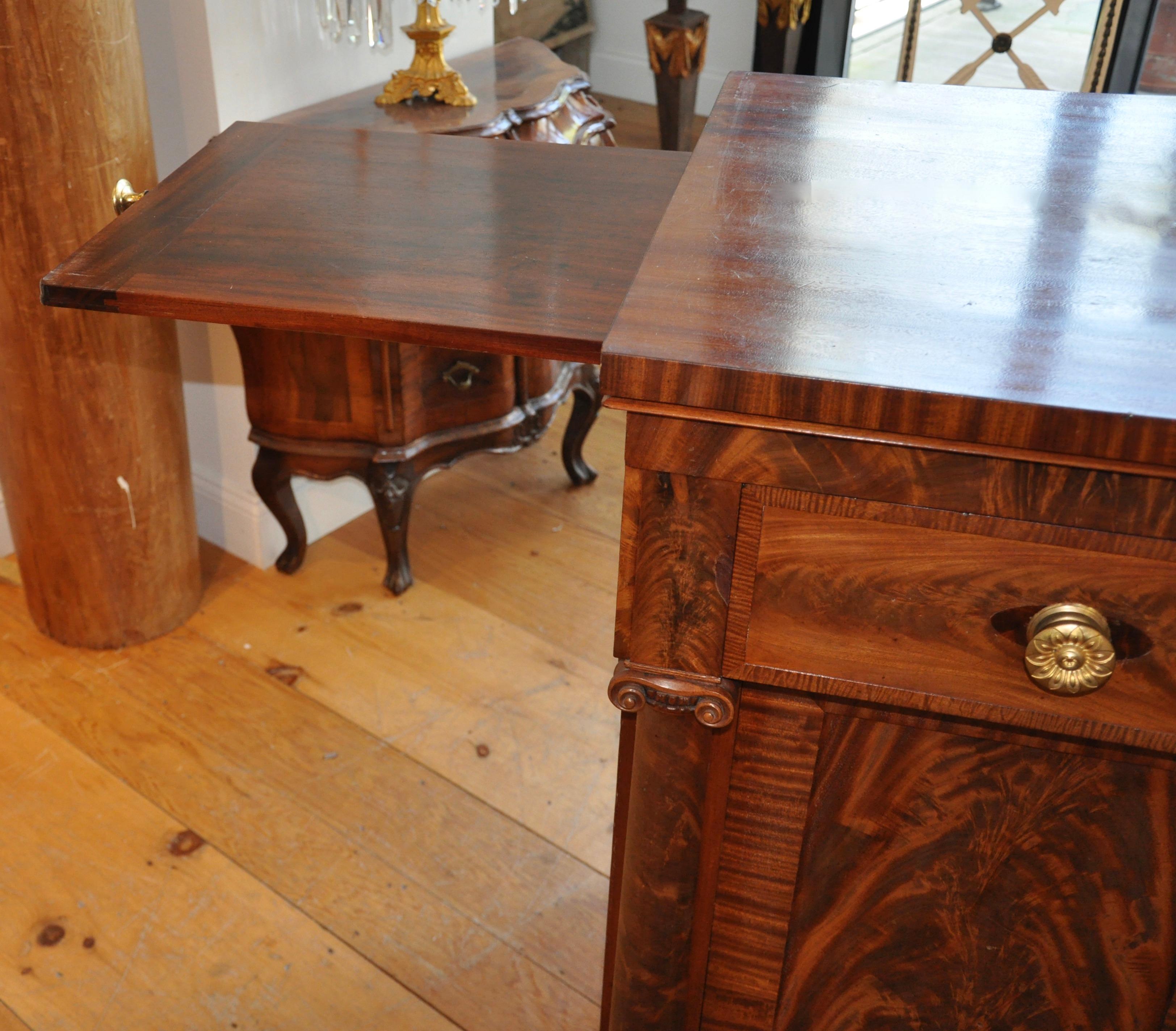 Book matched mahogany and mahogany veneered sideboard or serving cabinet of the period and influenced by Philadelphia Cabinetmaker, Antoine Gabriel Quervelle. Wonderfully carved columns and neoclassical bases, pull out slides for additional serving