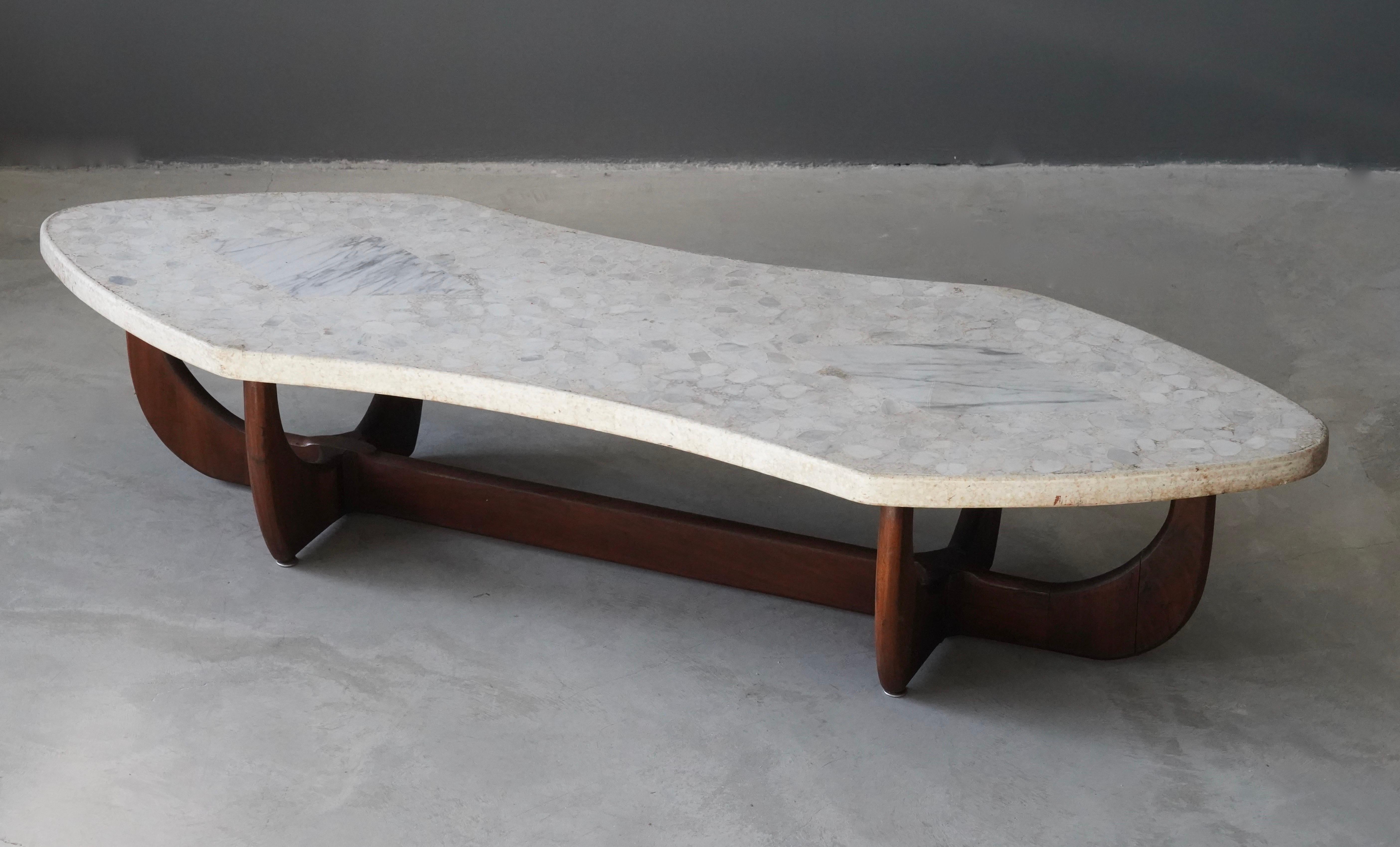 A sculptural coffee table / cocktail table. Designed and produced in America, 1950s. Stone top consisting of terrazzo with Carrara marble inlays, rests on a finely sculpted walnut base. 

Other designers of the period include Paul Frankl, Harvey