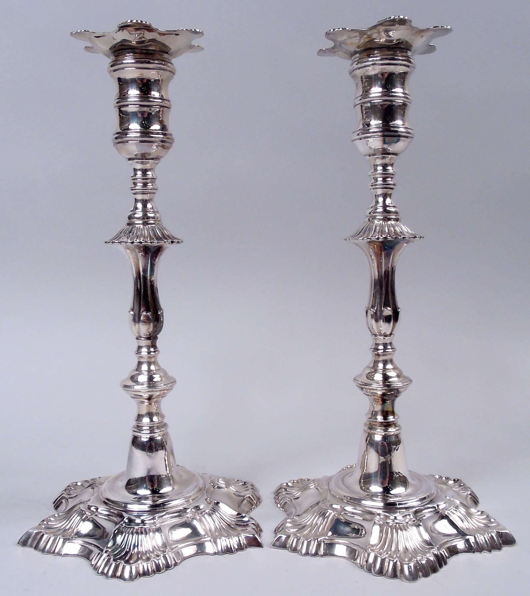 Paire de chandeliers traditionnels en argent sterling de l'époque coloniale américaine. Chaque : Douille à bobine sur tige de balustre, avec boutons et bride ; pied bombé. Six coquilles sur les rebords de la douille et du pied. Marqué 