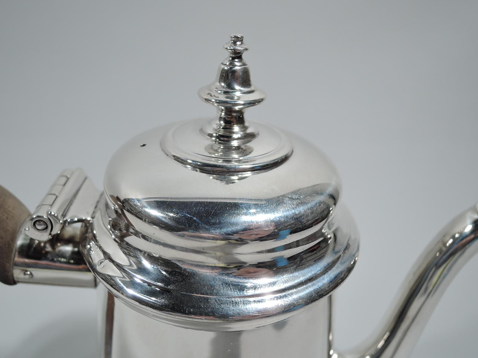 American colonial-style silver coffeepot. Made by Ensko in New York, ca 1950. Truncated conical body, s-scroll spout, hinged and domed cover with vasiform finial, and capped and double-scroll stained-wood handle. Fully marked including maker’s