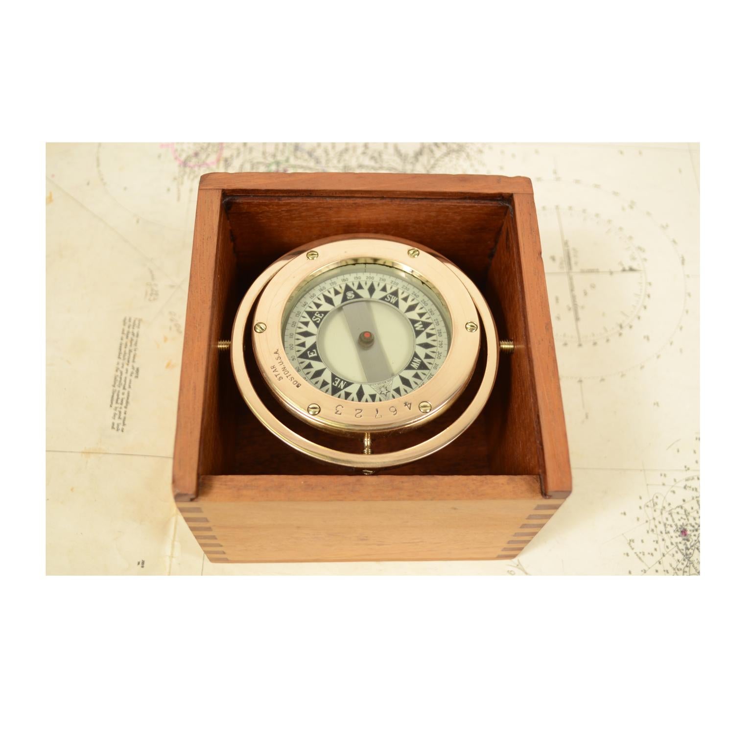 Liquid compass on universal joint signed STAR Boston 46723 from the early 1900s, complete with original wooden box with slot cover and mounted on a walnut board. The compass consists of a cylindrical box made of brass and bronze, on the bottom of