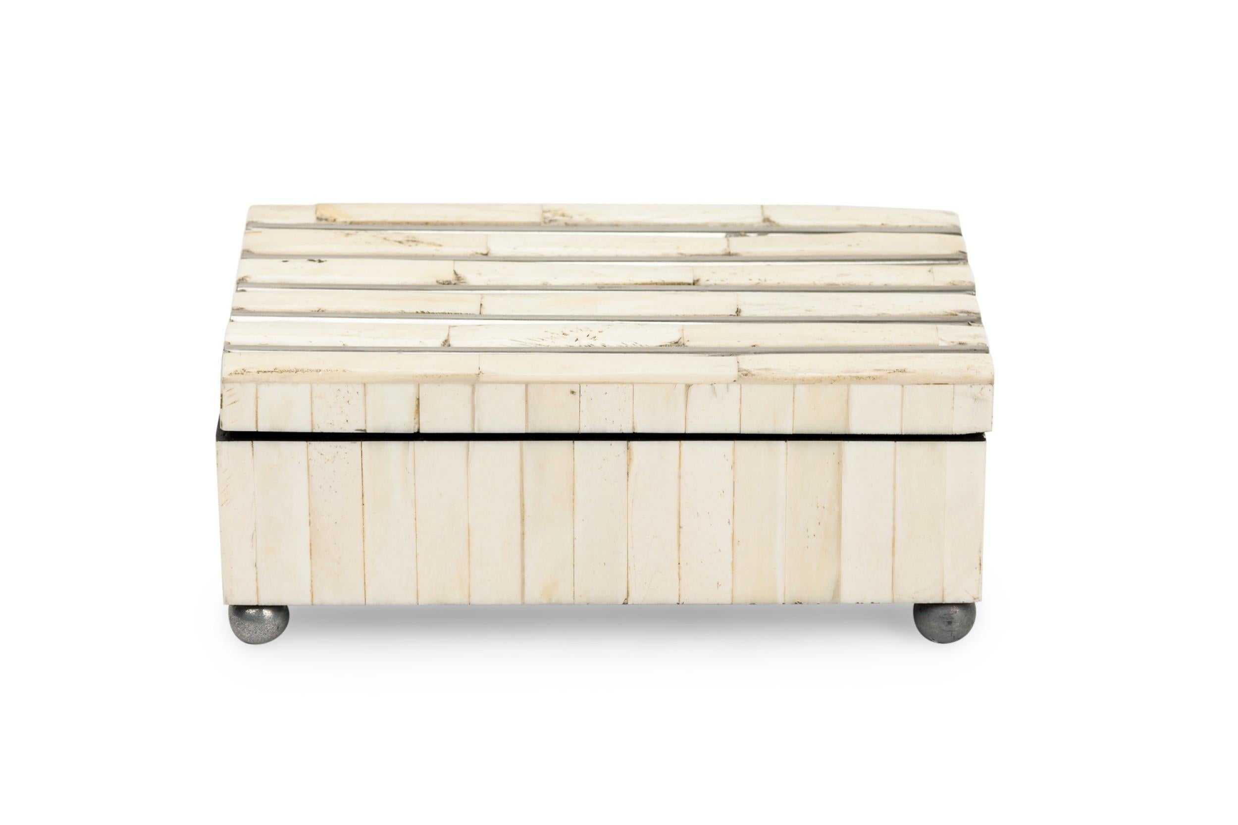 Scatola rettangolare decorativa in finto osso tessellato, contemporanea (anni '70), con un motivo orizzontale di bacchette argentate che attraversa la parte superiore e poggia su 4 piedini a sfera