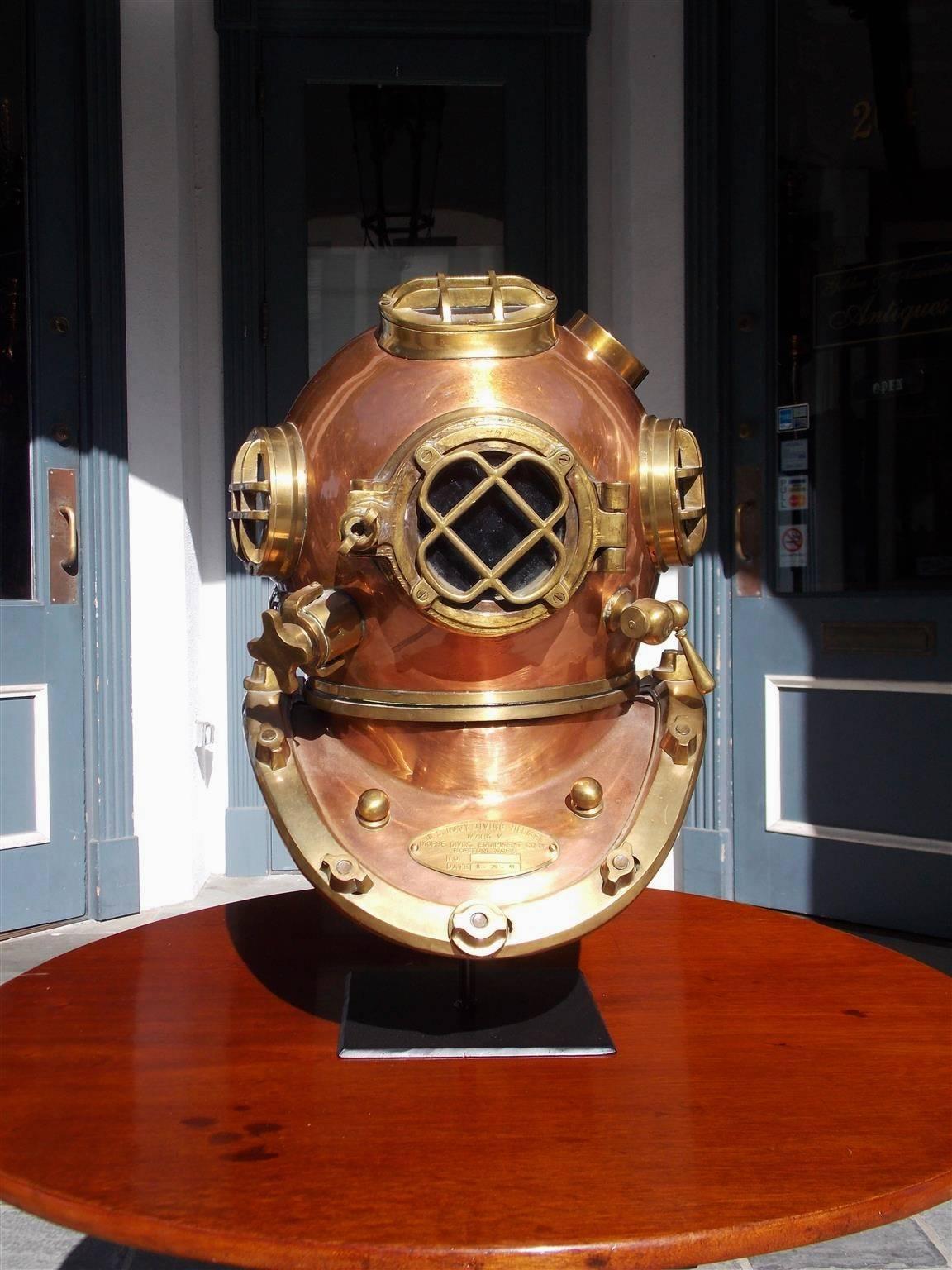 Réplique de casque de plongée naval américain en cuivre et laiton sur support électrifié avec quatre hublots en verre:: capot fileté:: prise d'air et ventilateur. Insigne estampillé Morse diving equipment Co. Mark V. Boston:: MA:: 8-29-41. Pièces
