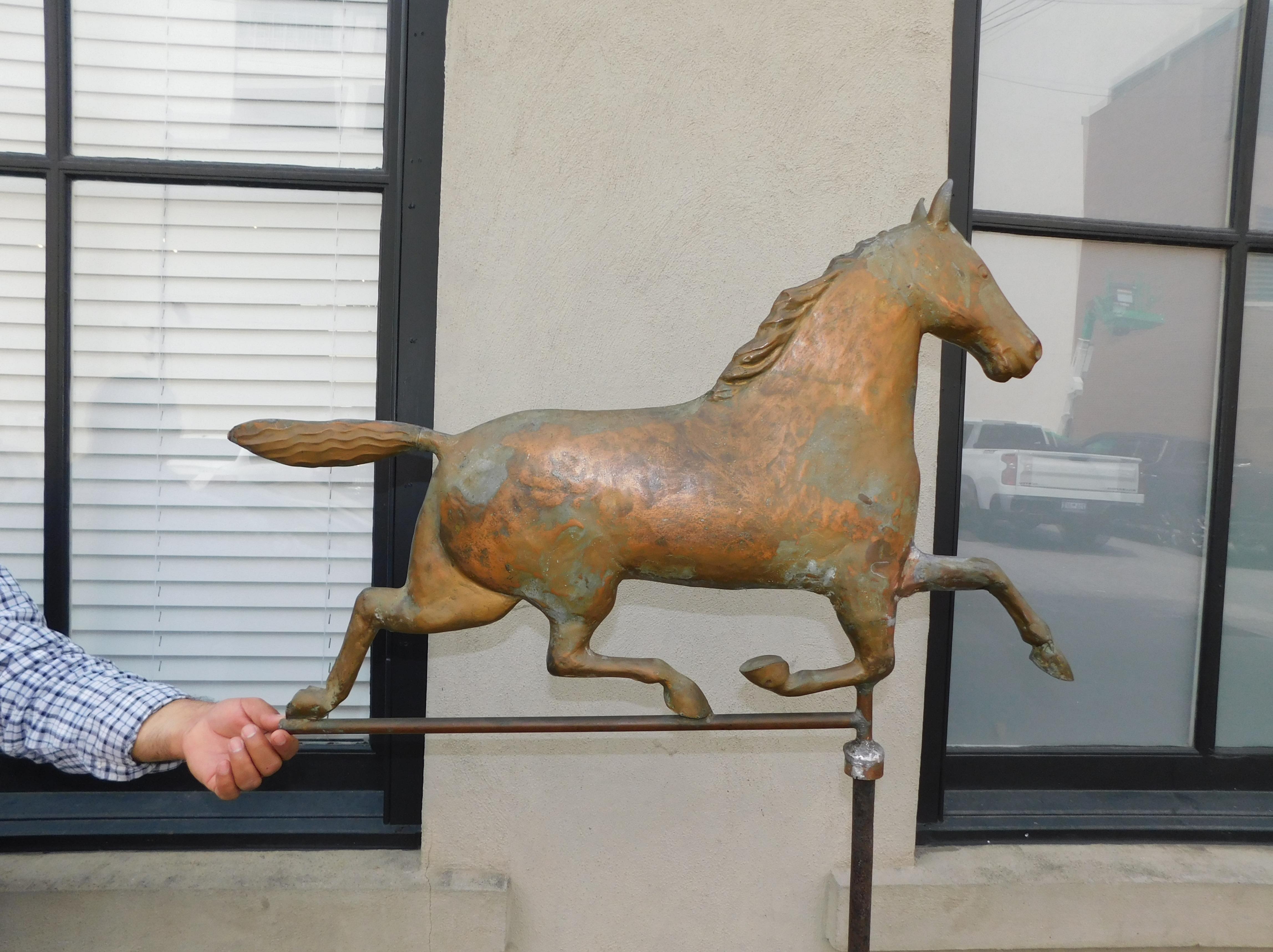 American Copper full bodied running horse weather vane with original central supporting wrought iron rod, rotating zinc directional, copper spheres, and resting on hand made iron stand, Late 19th Century