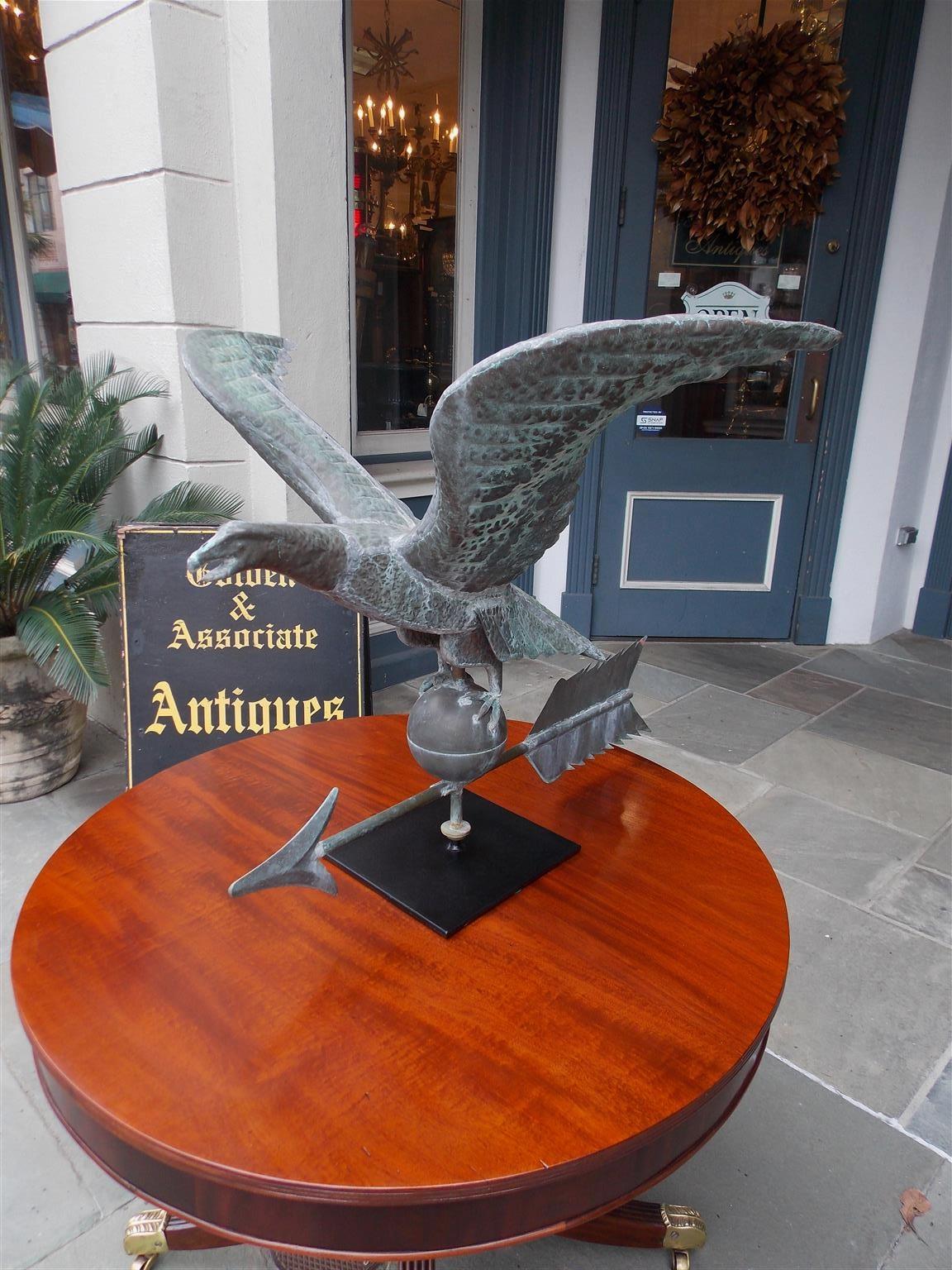 American molded copper spread winged eagle weathervane with circular sphere, arrow, and mounted on cast iron squared base. Weathervane has a fine natural verdigris patina in the original condition with a supporting rod on the rear of wings. Late