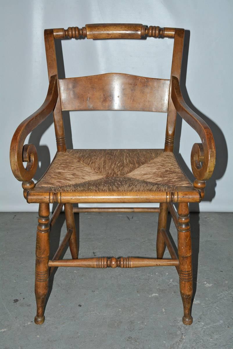 Cette chaise de bureau ou de salle à manger en bois avec assise en raphia tressé est dans le style Empire américain du début du XIXe siècle avec dossier et pieds tournés. Des tendeurs sécurisent les jambes.
Mesures : Hauteur des bras, 25