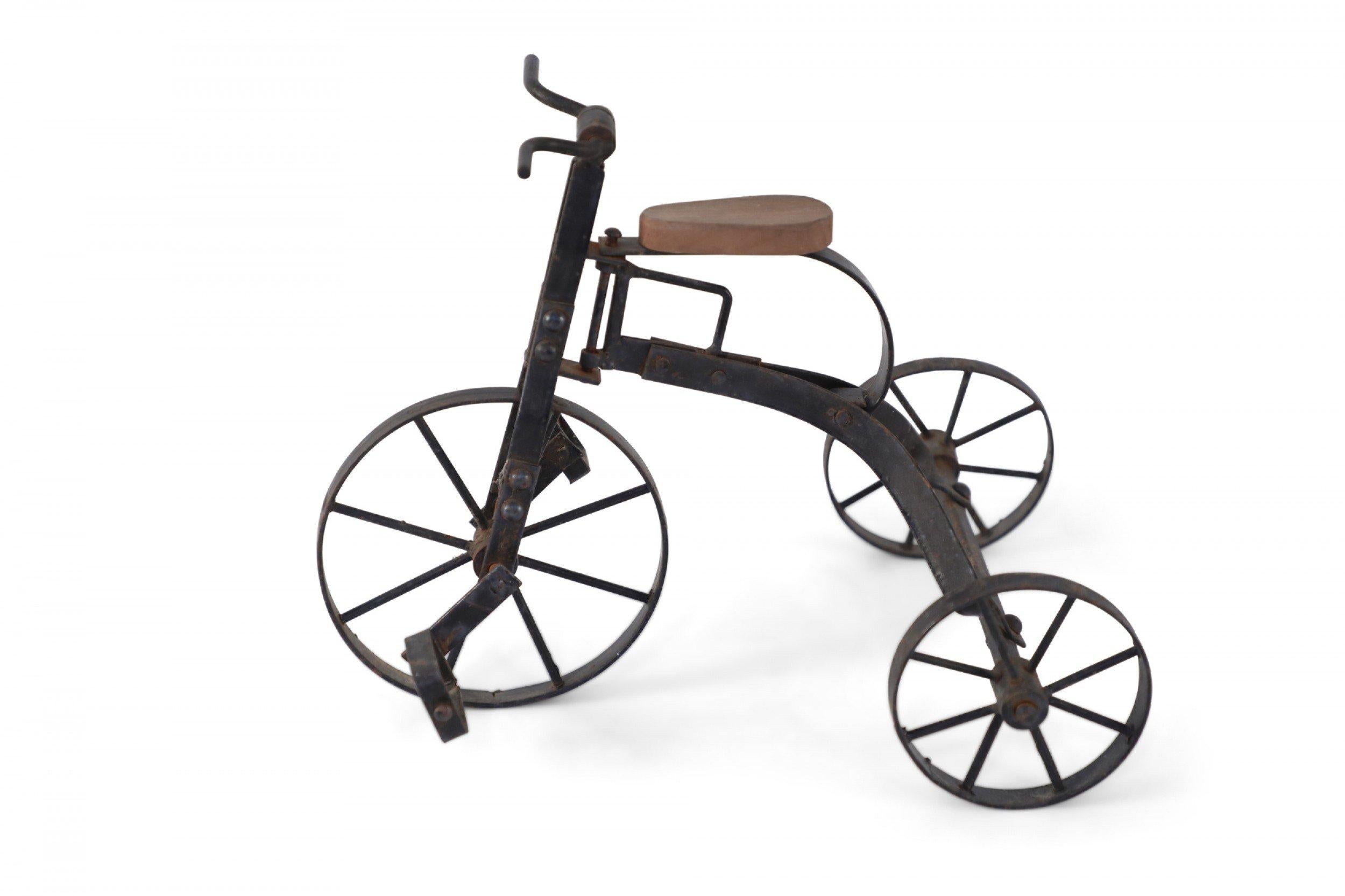 American Country-style rustic iron miniature tricycle sculpture with pine wood seat and rotating wheels and pedals.
       