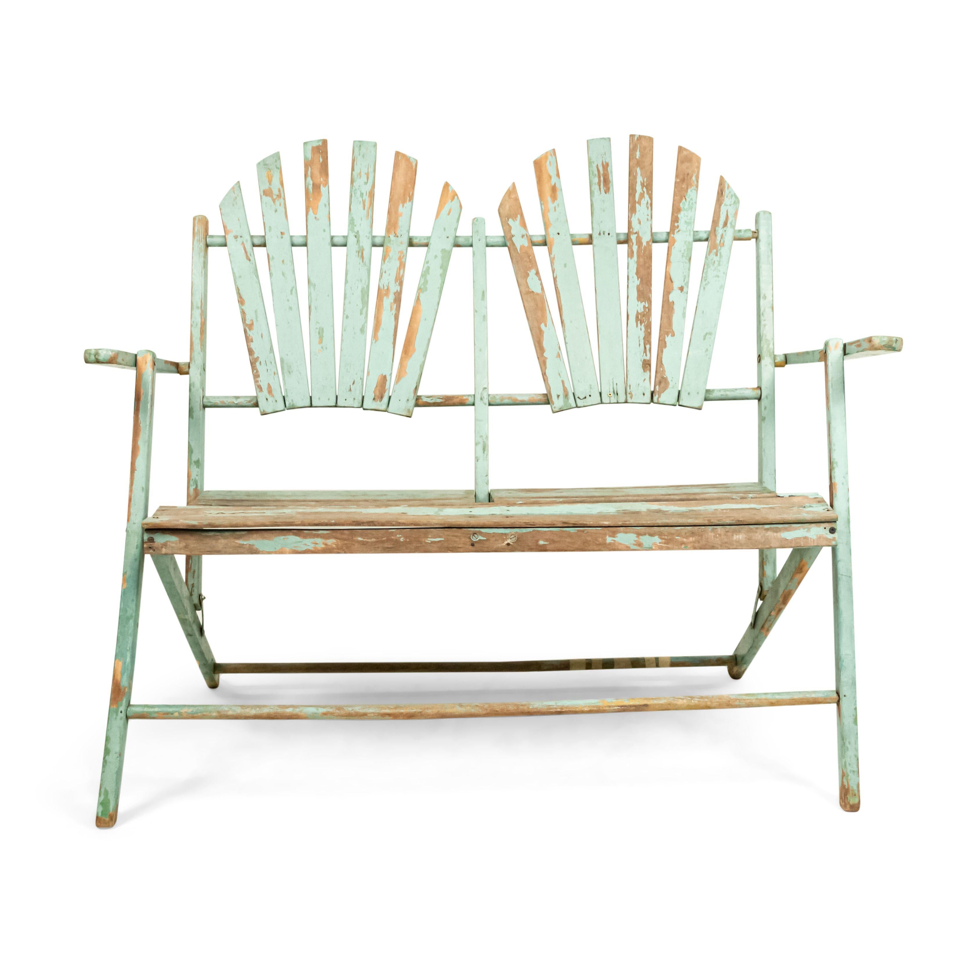 American Country style (19/20th Century) outdoor folding loveseat with a weathered green painted slat design seat and double fan back back.
 