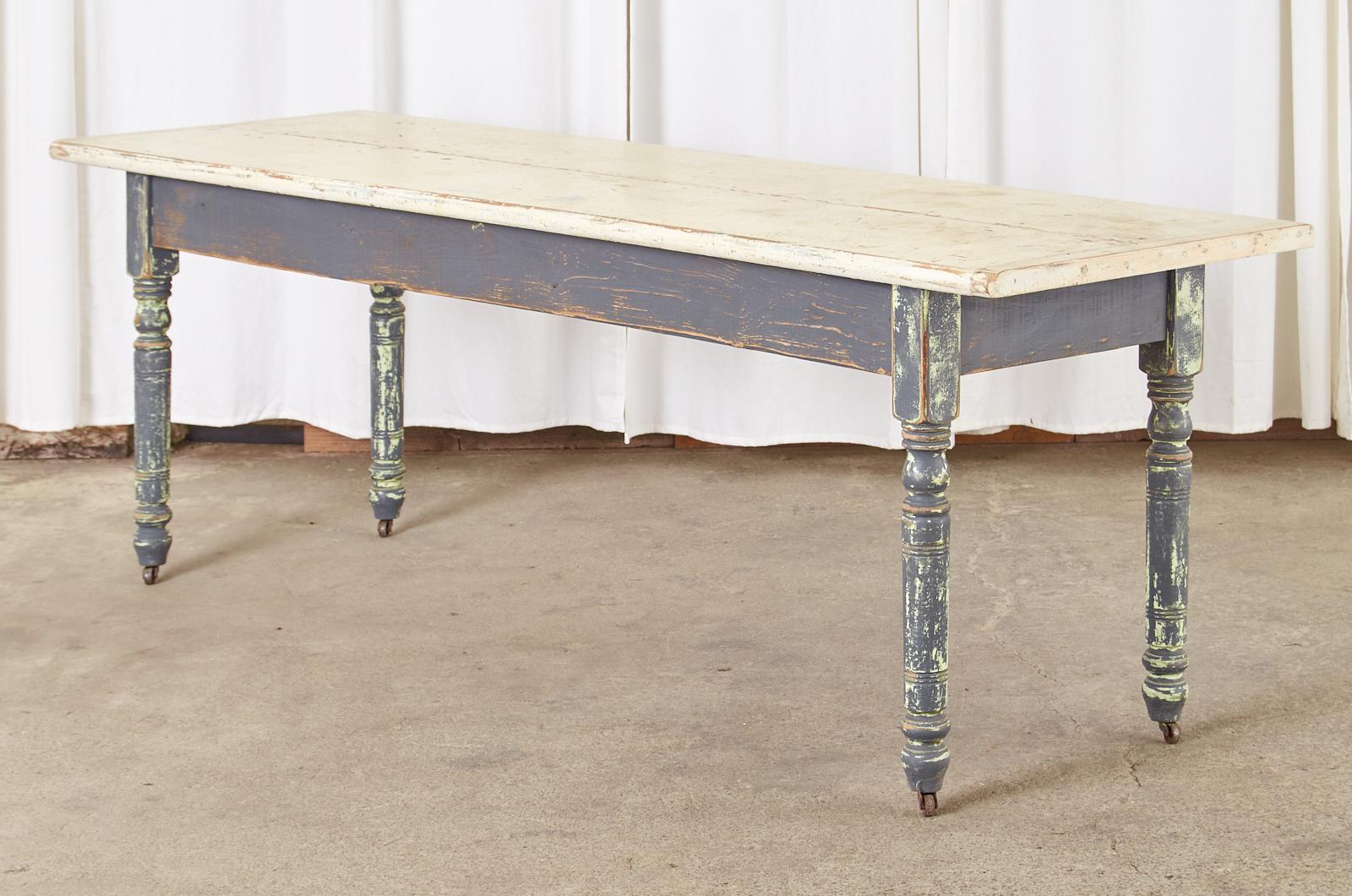 Large, rustic American country farmhouse dining table, harvest table, or console table crafted from reclaimed pine. The table has a 1.5 inch thick two-plank top with breadboard ends. The vintage paint has an aged patina with craquelure on the