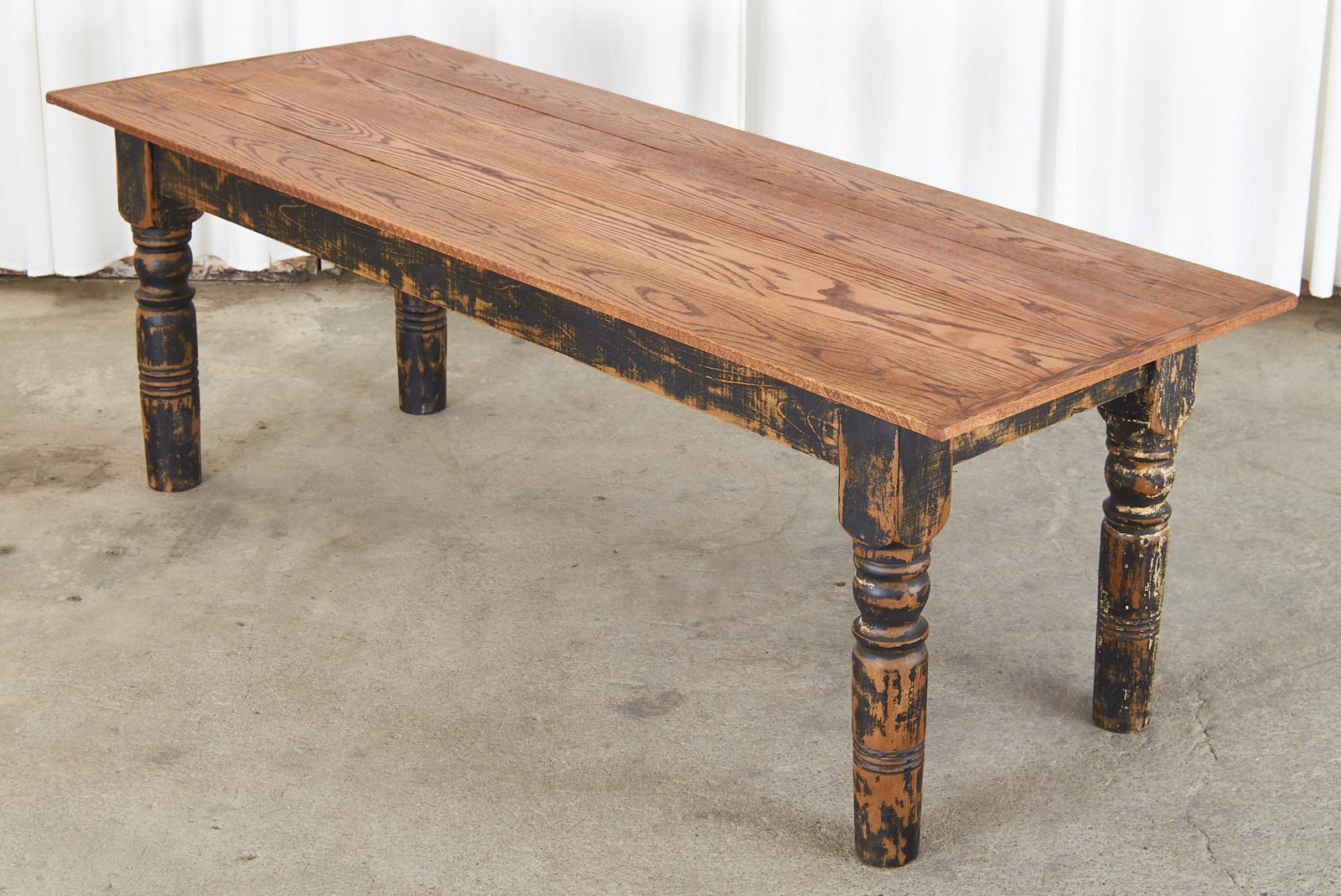 Rustic American country farmhouse dining table or harvest table featuring a 92 inch long oak plank top with bread board ends. The base is crafted from thick reclaimed painted pine boards and supported by massive 5 inch thick square legs with a