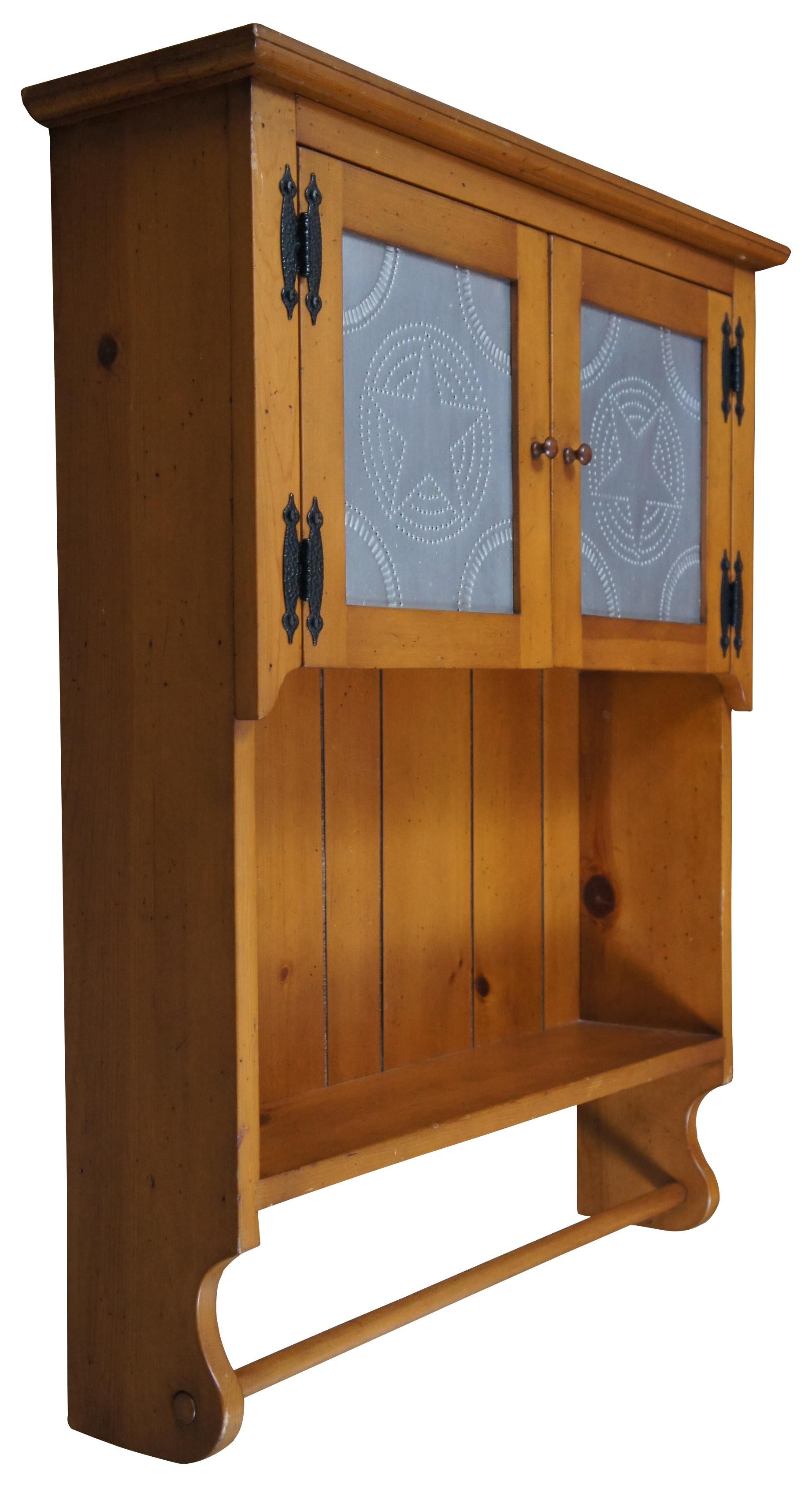 Country style wall hanging cabinet with towel bar and star stamped tin panels on the doors.
  