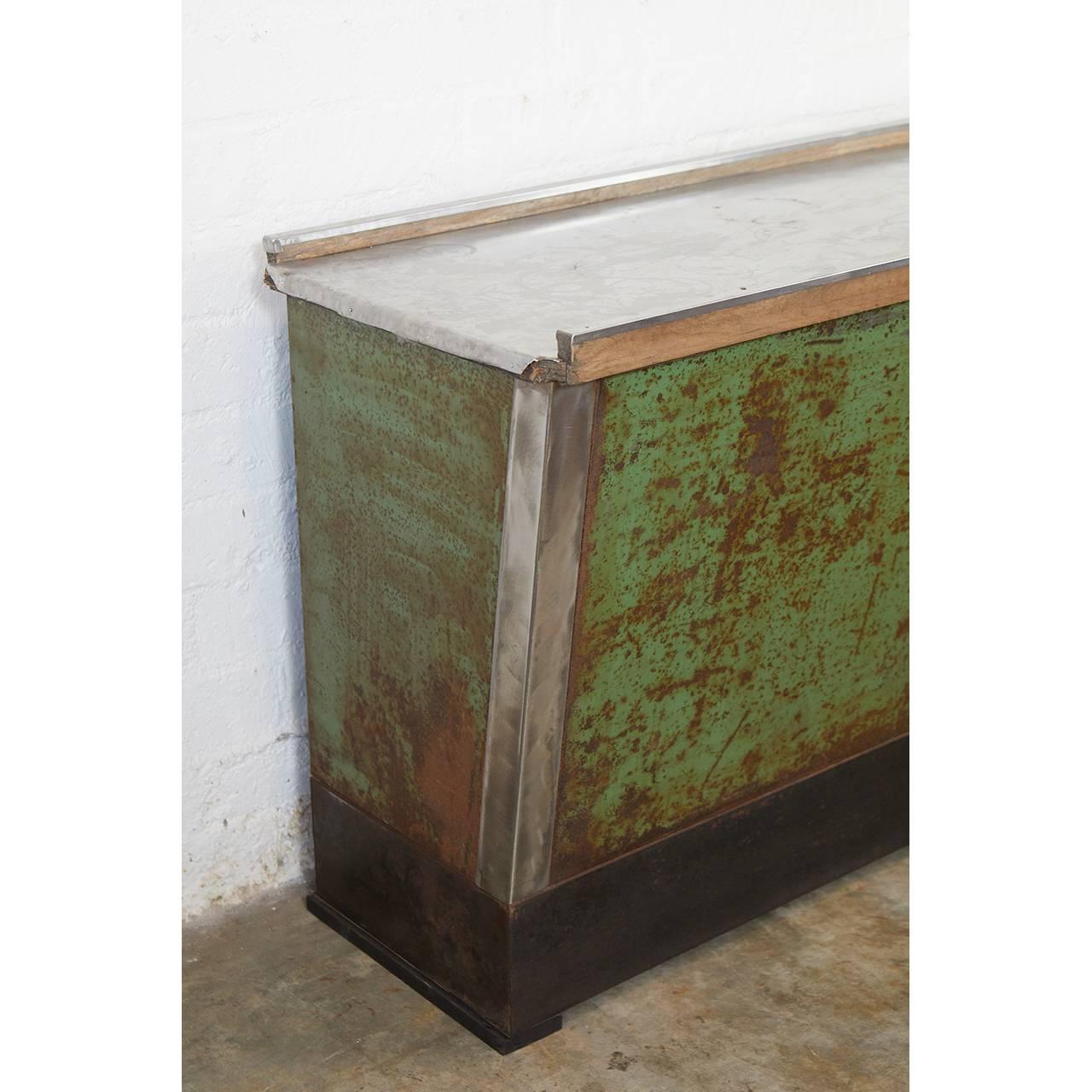 This American country store counter is from New England. From the distressed patina we assume that it was used as an outdoor porch counter. The piece tapers nicely from top to bottom and has two shelves at the back. The brushed stainless steel sheet