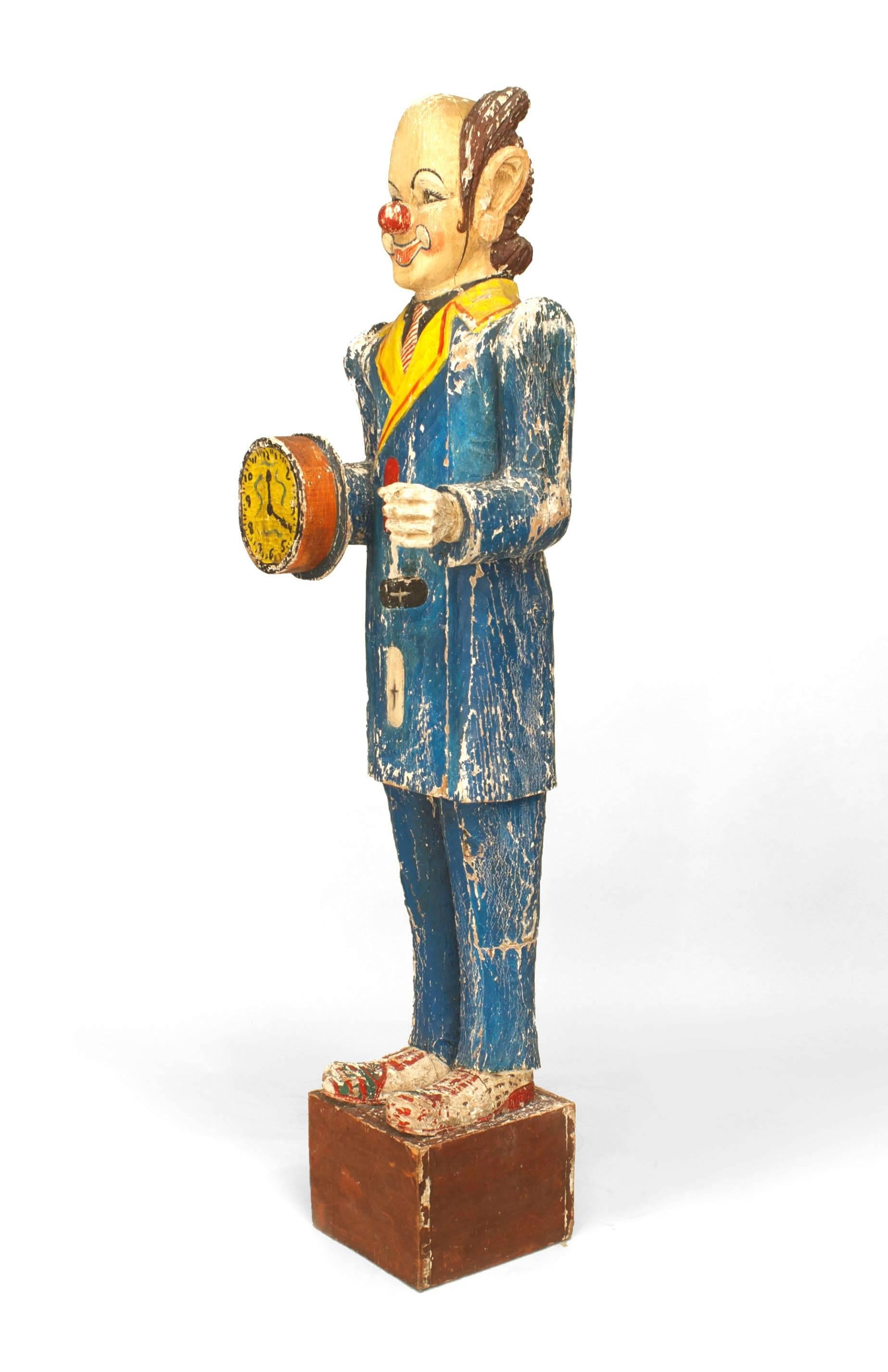 Figure en bois sculptée grandeur nature d'un clown de cirque tenant un chapeau à visière, de style country américain (milieu du 20e siècle), avec une surface gesso et peinte (probablement fabriquée par Boston Carving Co.)

