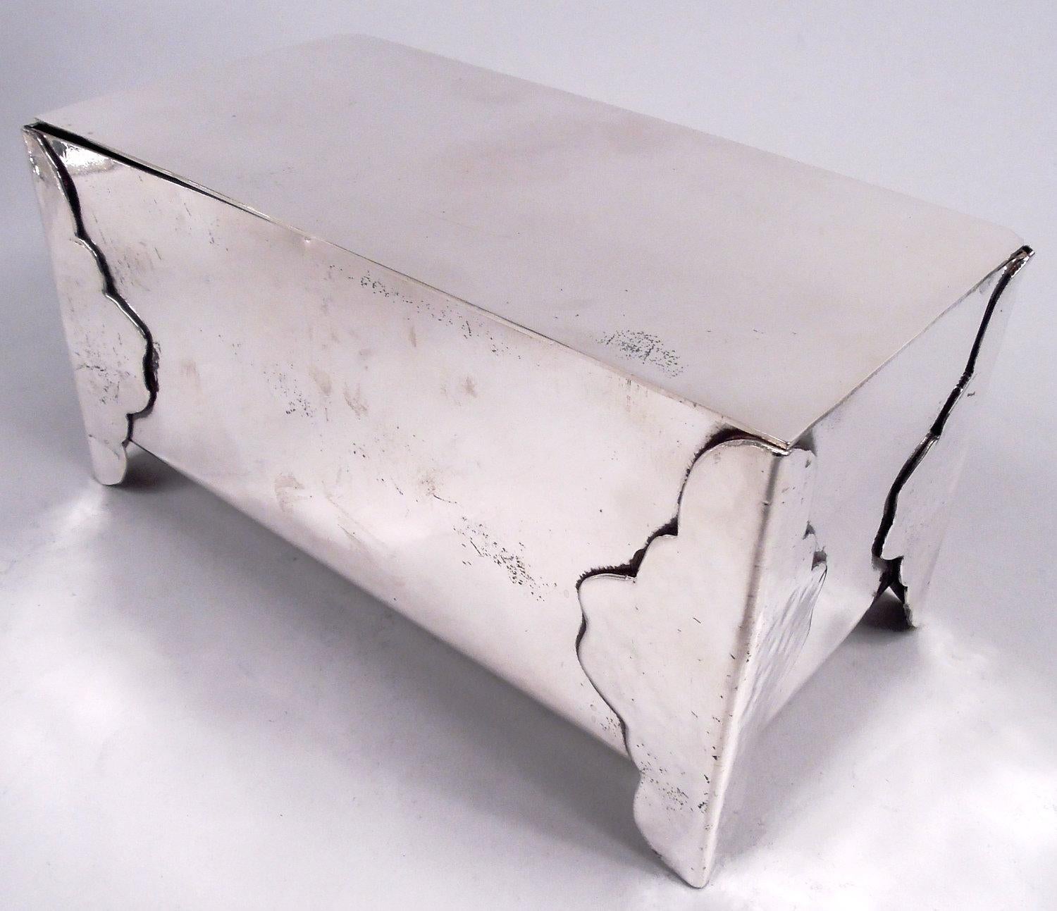 Cofre gótico americano de plata de ley, hacia 1920. Rectangular liso con lados rectos y tapa plana abatible. Monturas festoneadas martilladas a mano, dobladas en las esquinas y terminadas en soportes. Parte inferior con la inscripción 