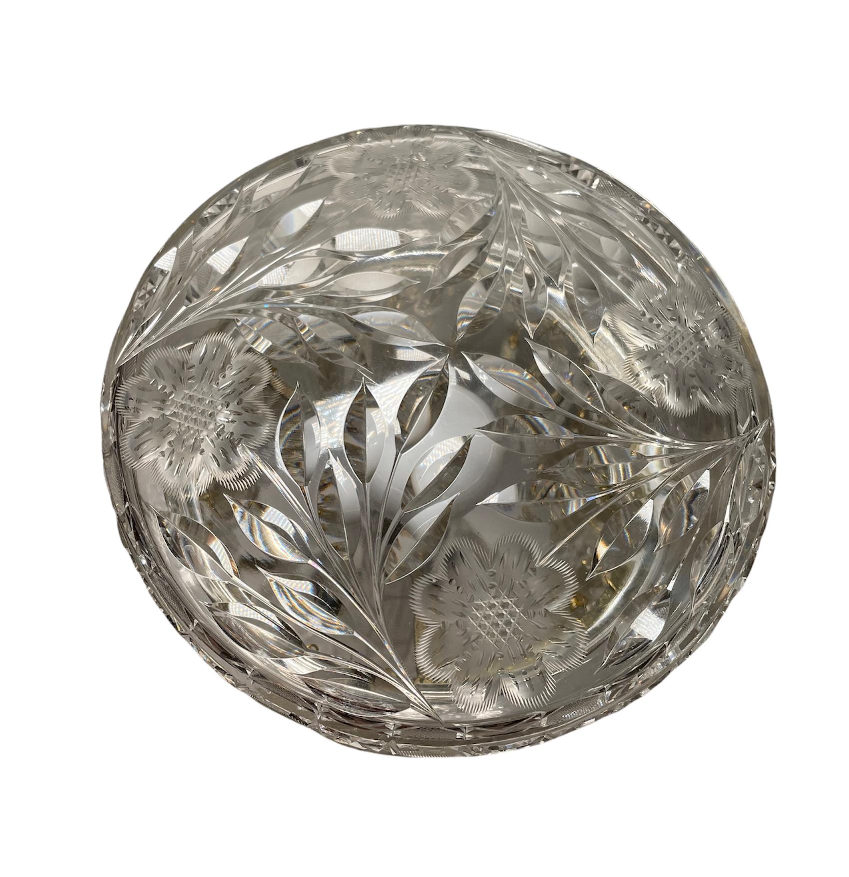 This is a cut crystal mushroom shaped small table lamp. The lamp consists of a shade and a column with a round base. The lamp shade and base are adorned with etched branches of leaves and flowers with eighth petals. The borders of them are decorated