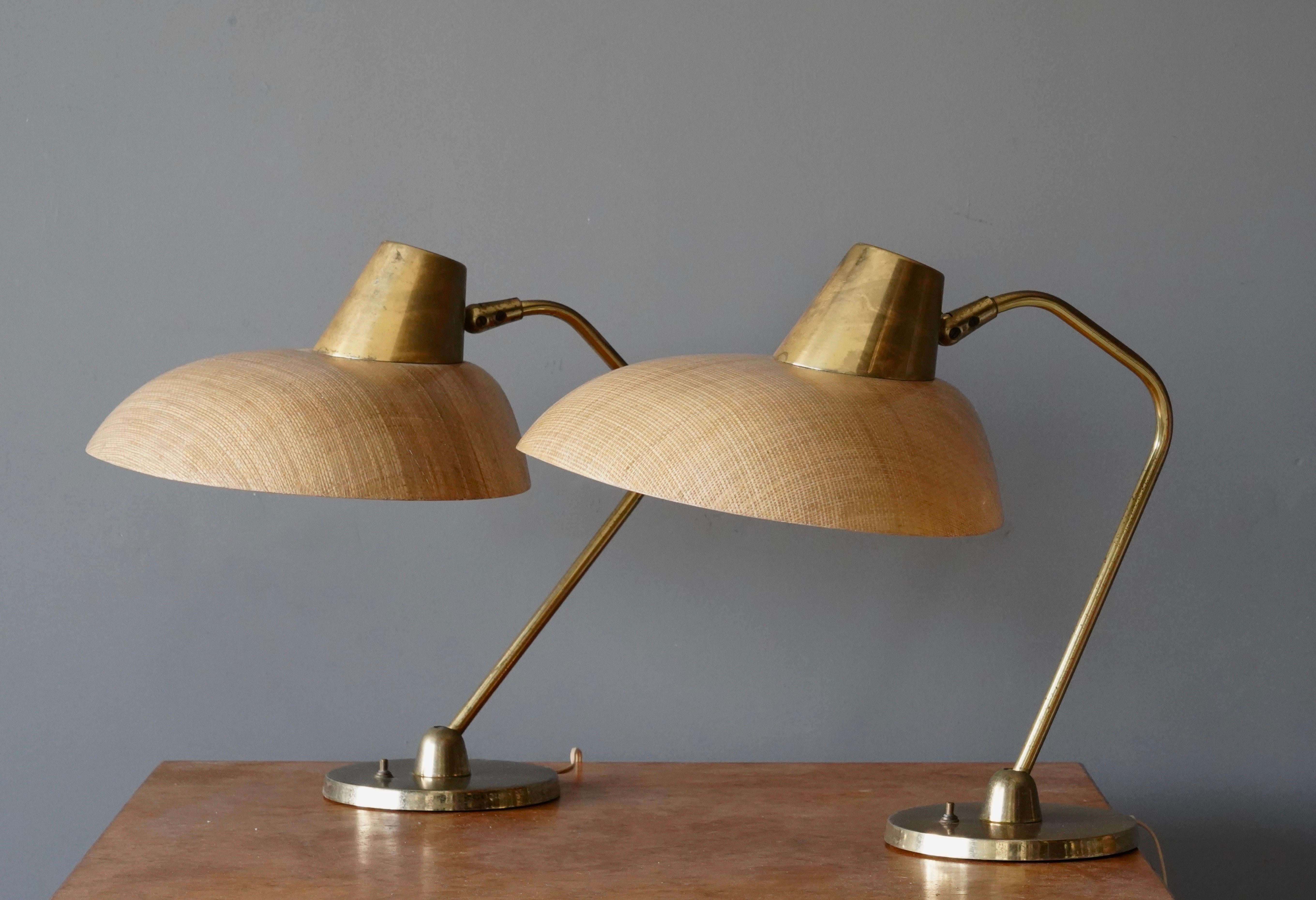 A pair of adjustable table lamps / desk lights. Features brass and original sizable lampshades in raffia and fiberglass. 

Takes one lightbulb on standard medium socket. No stated max wattage. 

Other designers of the period include Paavo