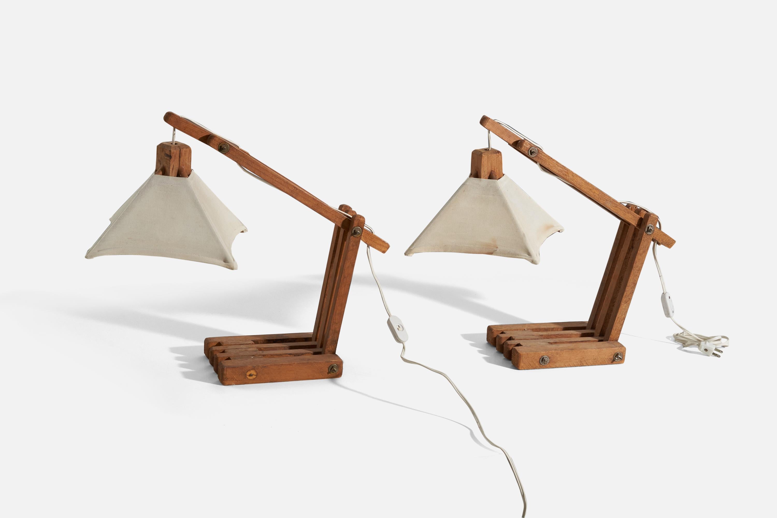 Une paire de lampes de table réglables en chêne et abat-jour en tissu, conçues et produites en Amérique, années 1970.

Les abat-jour sont inclus dans l'achat.
Dimensions variables. Les dimensions indiquées se réfèrent aux lampes de table montées