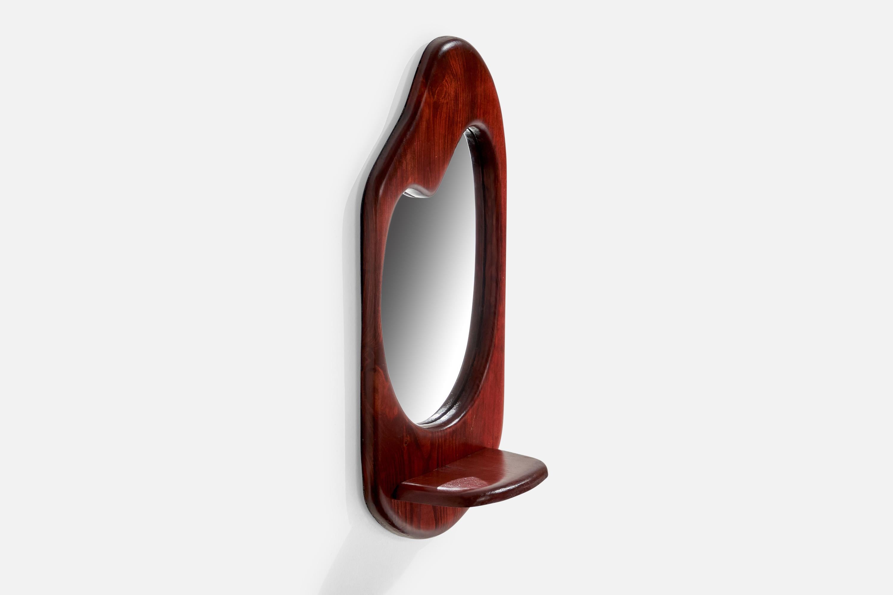A stained oak freeform wall mirror with small shelf, designed and produced in the US, c. 1970s.