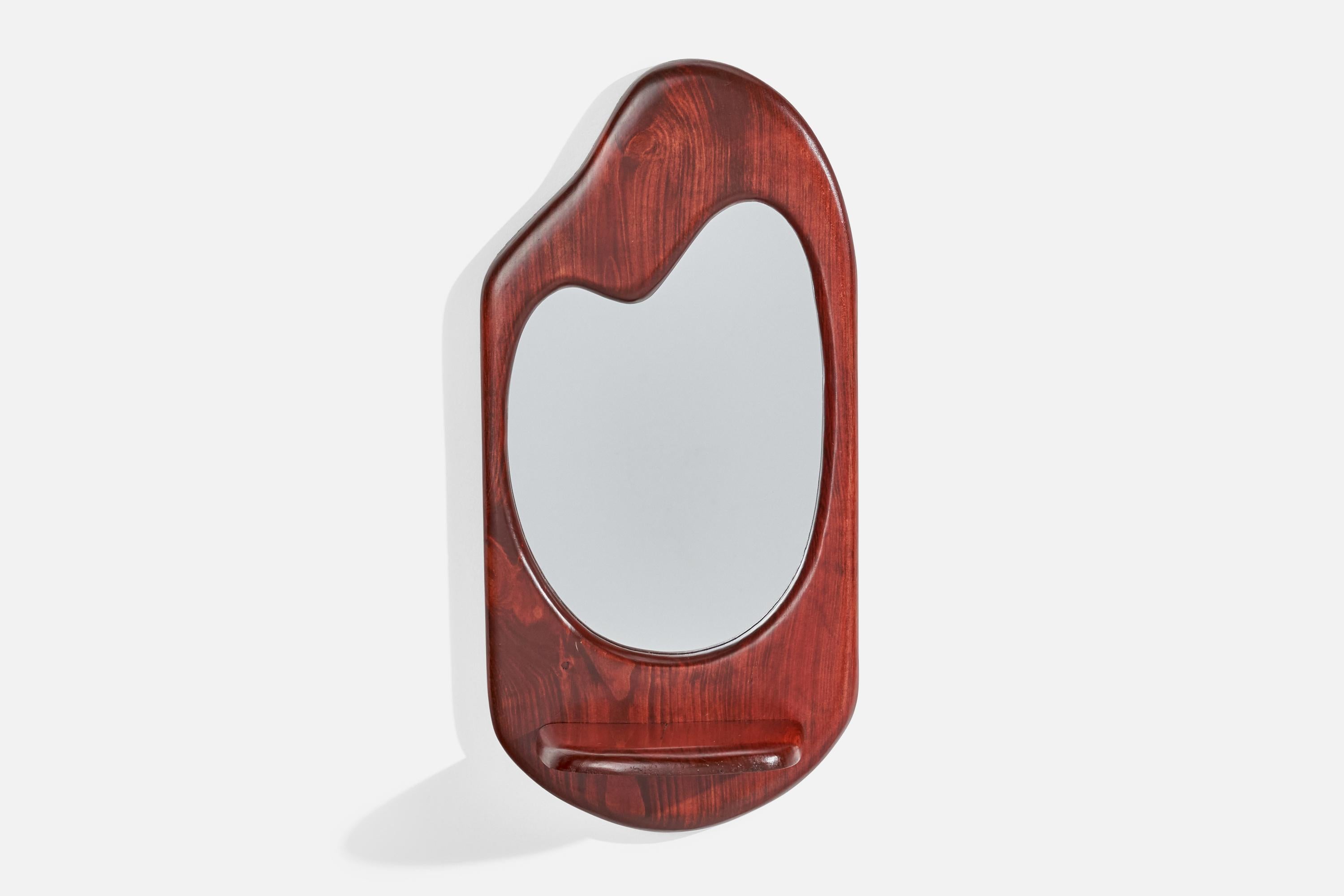A stained oak freeform wall mirror with small shelf, designed and produced in the US, c. 1970s.