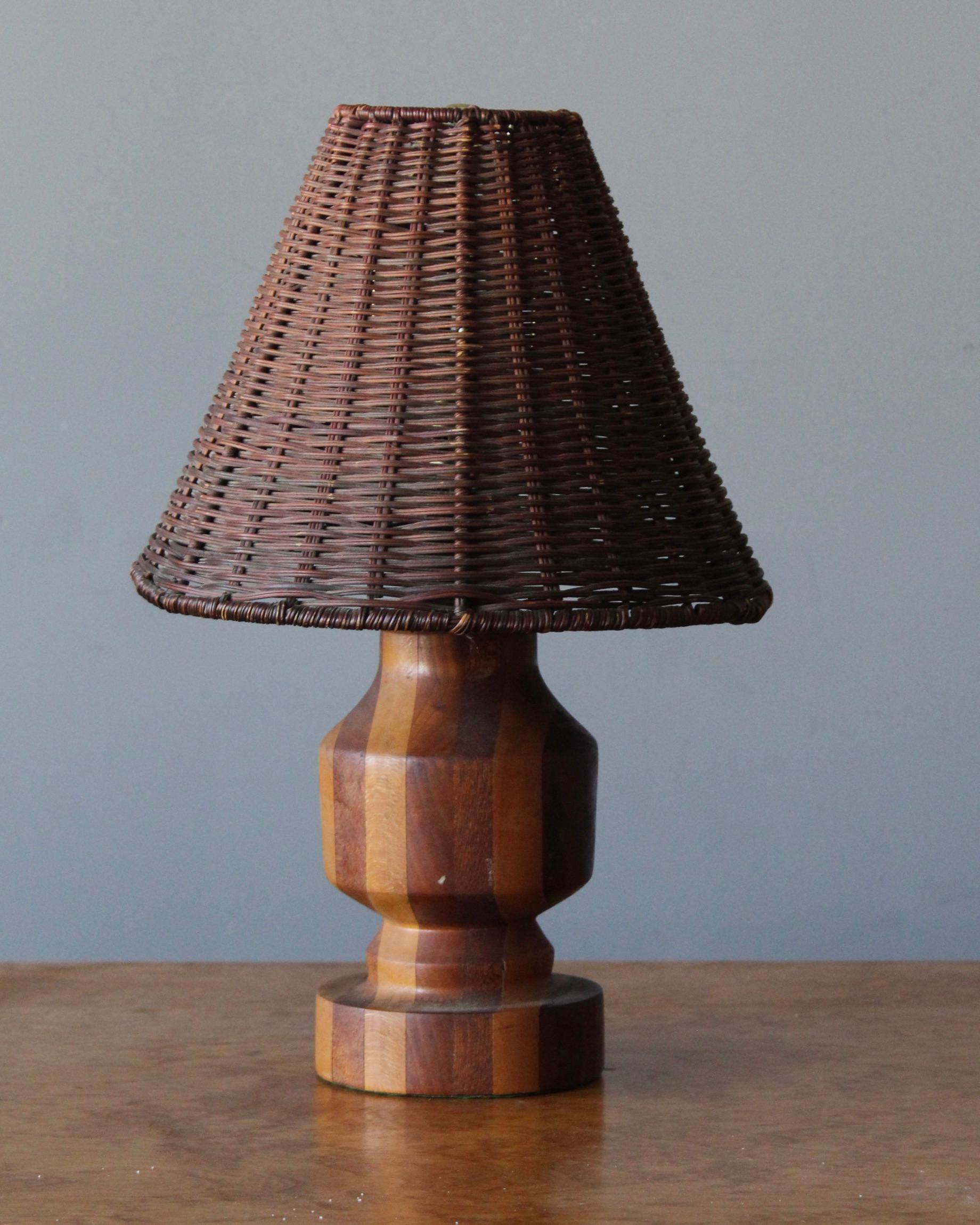 A table lamp, designed and produced in United States, 1960s. Features finely turned solid woods of different species. brass, assorted vintage rattan lampshade. With beautiful original patina.

Stated dimensions include lampshade. Illustrated