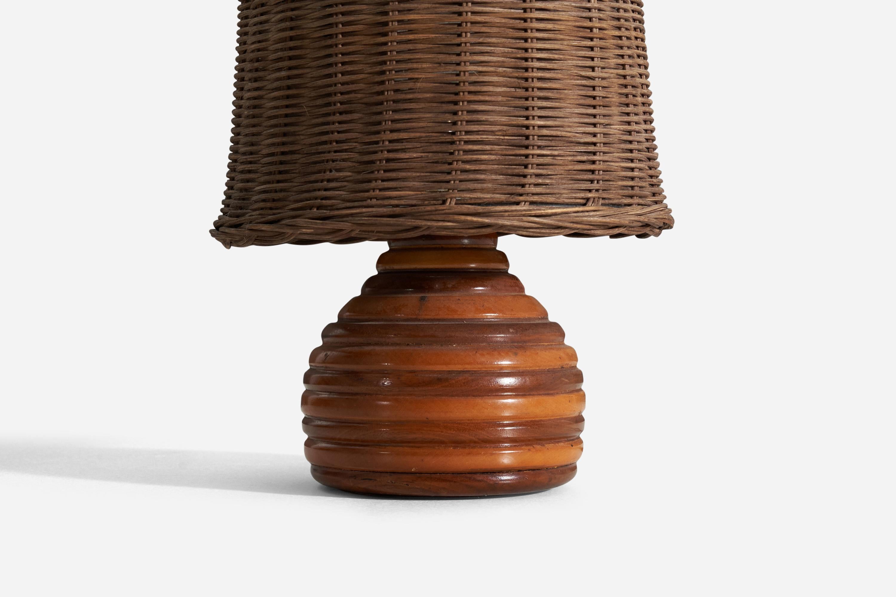 A table lamp. In finely carved wood. Designed and produced by unknown maker. Presents with beautiful original patina to wood and brass.

Sold with an assorted vintage rattan lampshade lampshade. Stated dimensions including lampshade as is
