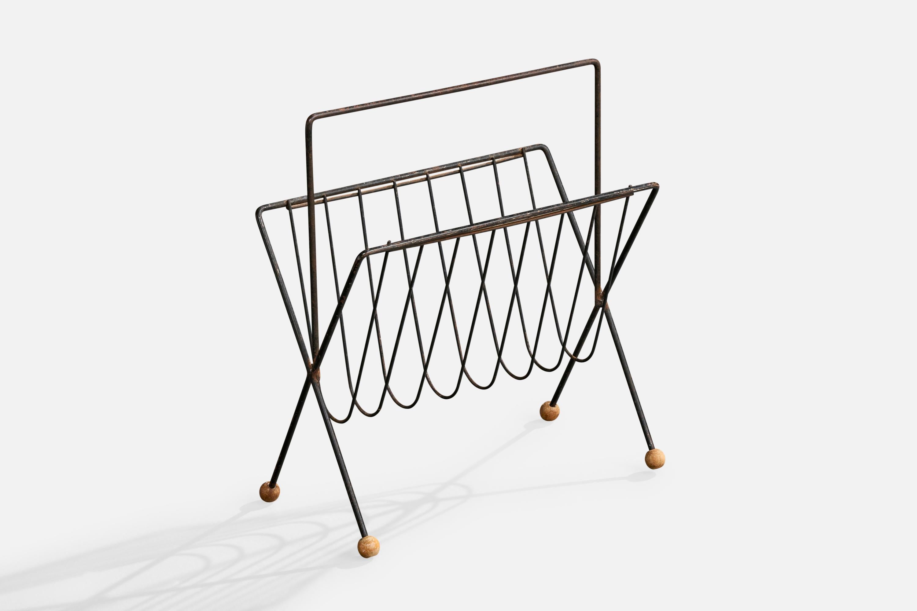 An iron and wood magazine stand designed and produced in the US, c. 1950s.

Heavy oxidation present throughout metal.

Overall Dimensions (inches): 20.0
