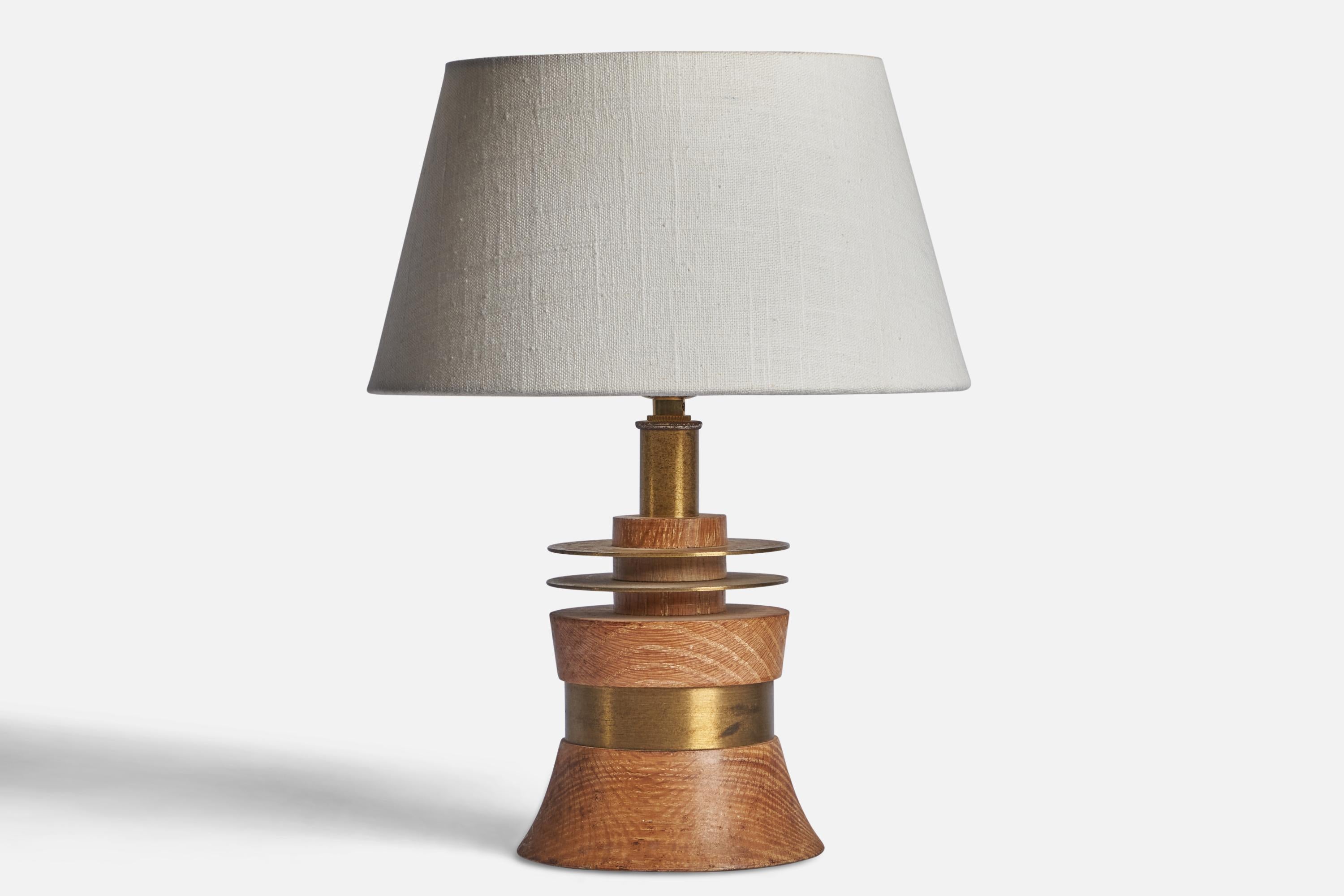 A brass and oak table lamp designed and produced in the US, 1950s.

Dimensions of Lamp (inches): 10” H x 5.15” Diameter
Dimensions of Shade (inches): 7” Top Diameter x 10” Bottom Diameter x 5.5” H 
Dimensions of Lamp with Shade (inches): 13.25” H x