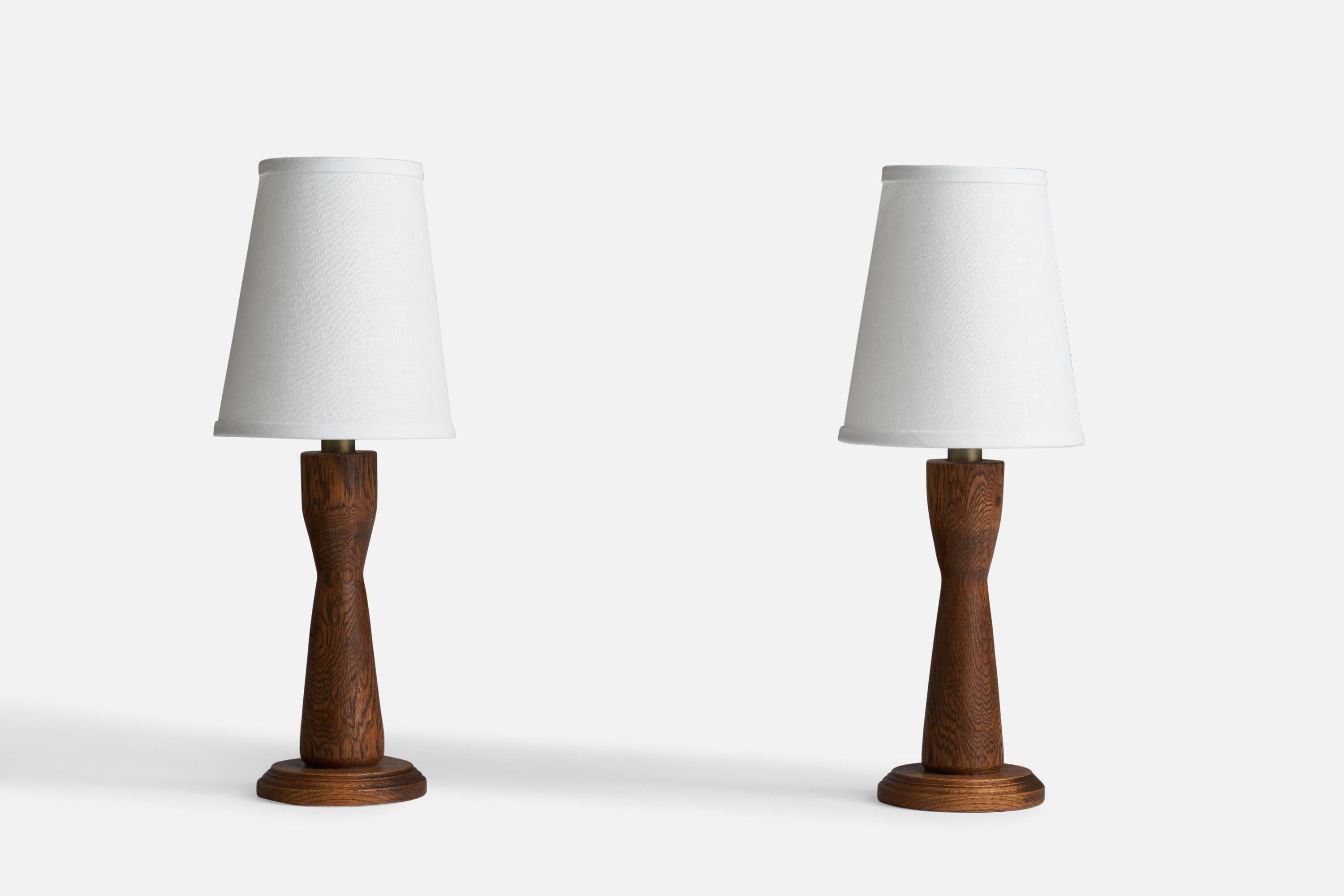 A pair of dark-stained oak and brass table lamps designed and produced in the US, 1950s.

Dimensions of Lamp (inches): 10.25” H x 4.25”  Diameter
Dimensions of Shade (inches): 4”  Top Diameter x 6”  Bottom Diameter x 7” H
Dimensions of Lamp with