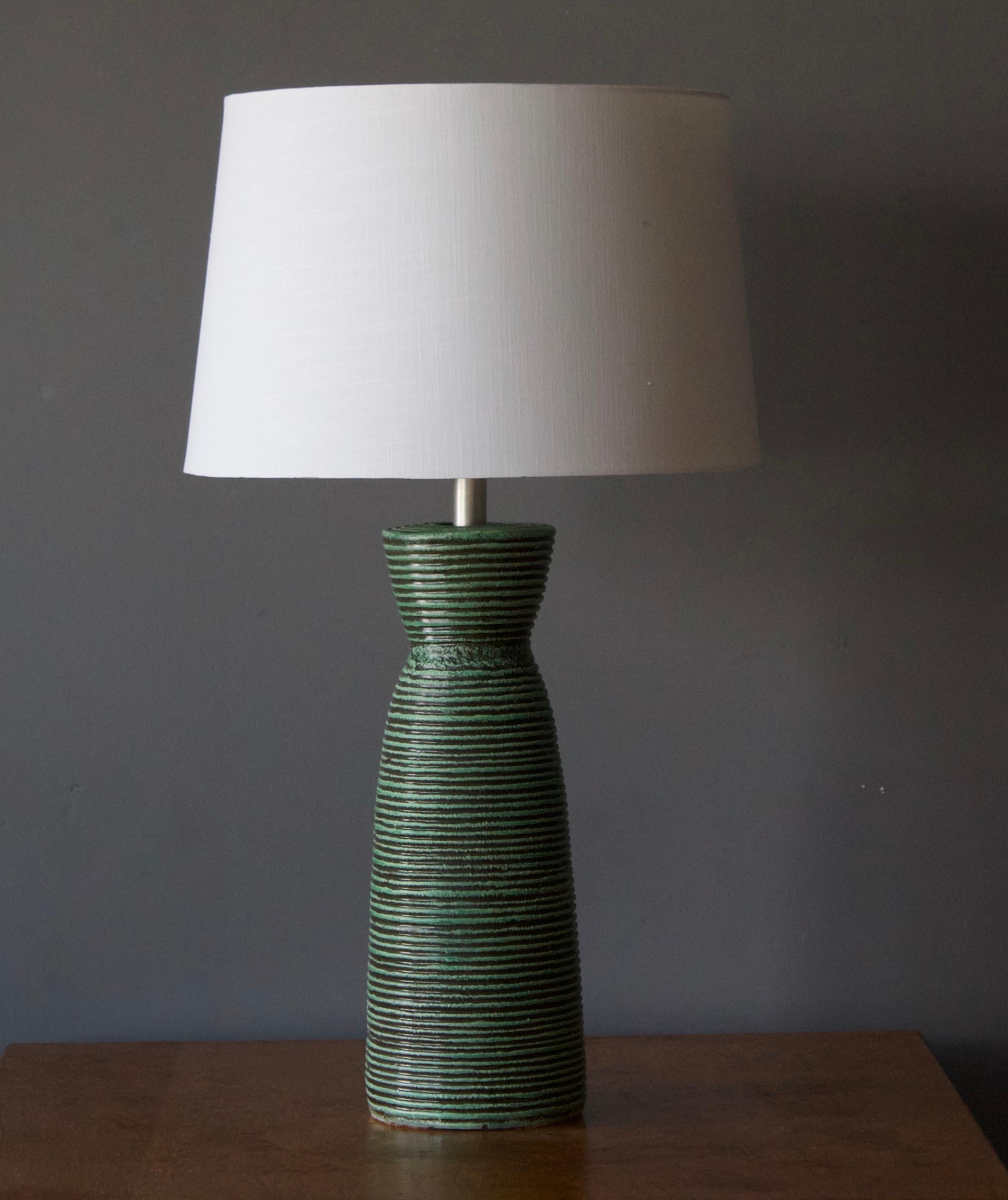 A pair of large table lamps, designed and produced by unknown American Designer, Artists studio, America, c. 1950s.

Features incised and green glazed / painted ceramic bases, metal stems. 

Other designers of the period include Claude Connover,