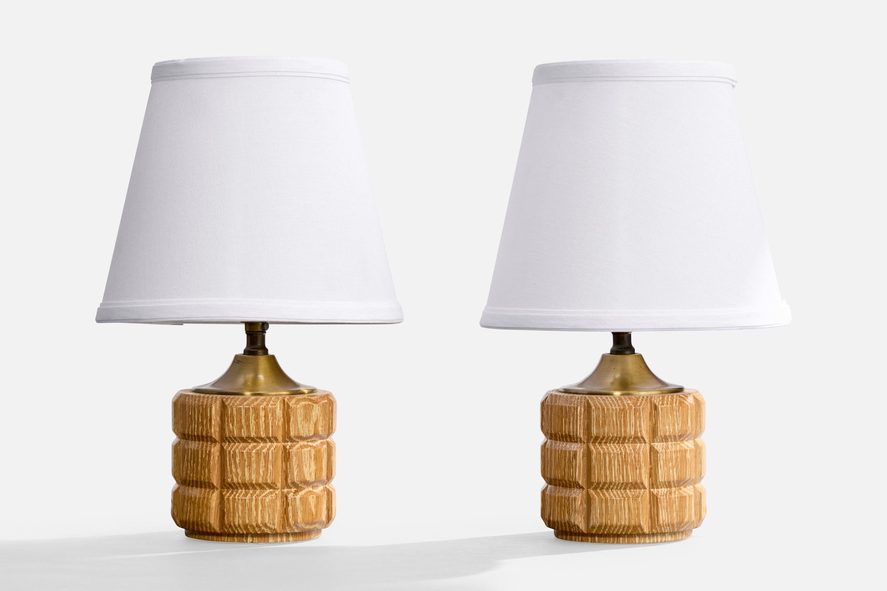 A pair of carved oak and brass table lamps designed and produced in the USA, c. 1950s.

Dimensions of Lamp (inches): 8.25” H x 4.25” Diameter

Dimensions of Shade (inches): 5” Top Diameter x 8” Bottom Diameter x 7” H 

Dimensions of Lamp with Shade