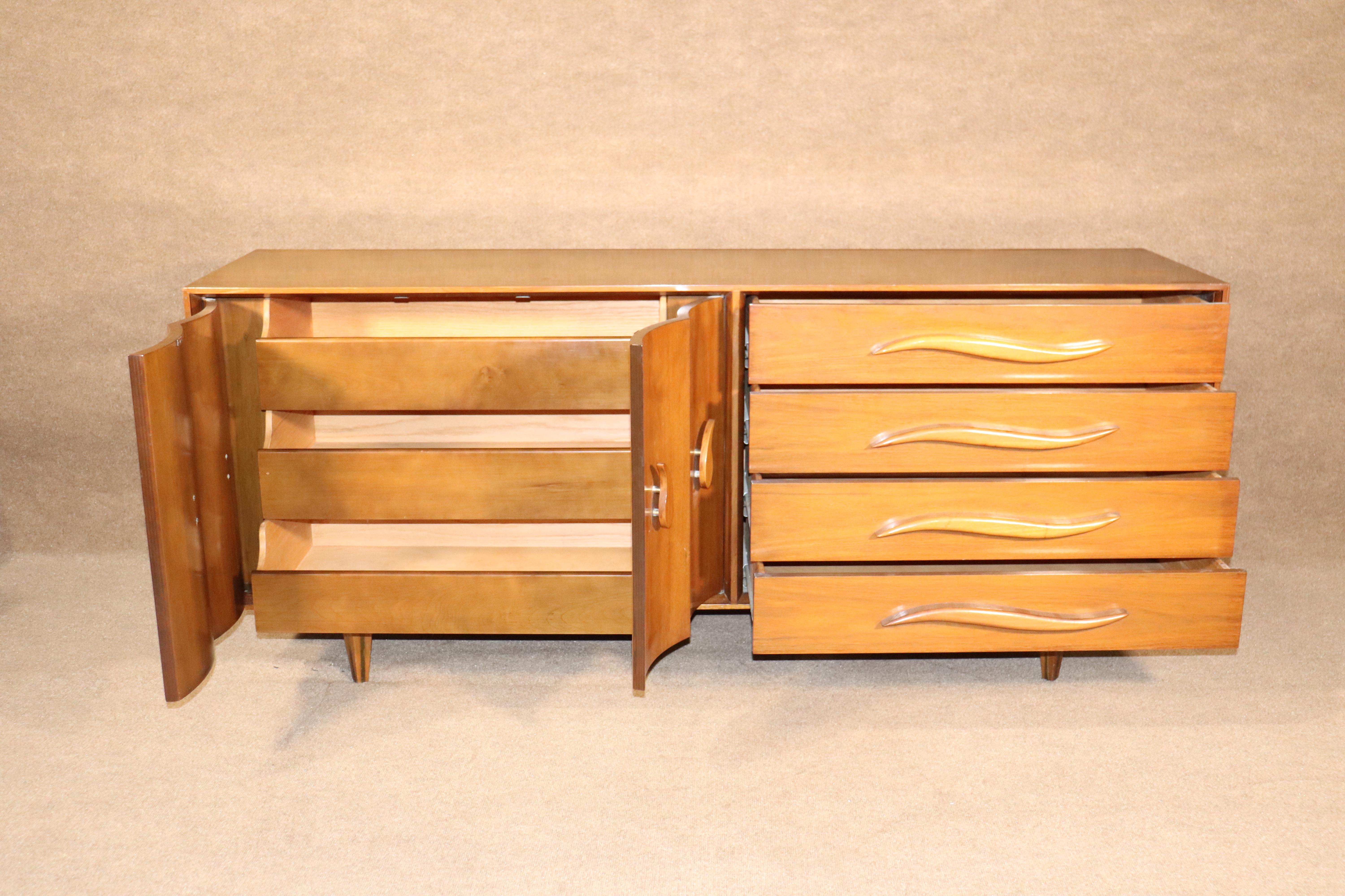 Mid-century modern dresser in walnut with seven wide drawers. Unique design with sculpted handles and brass inlay legs.
Please confirm location.
