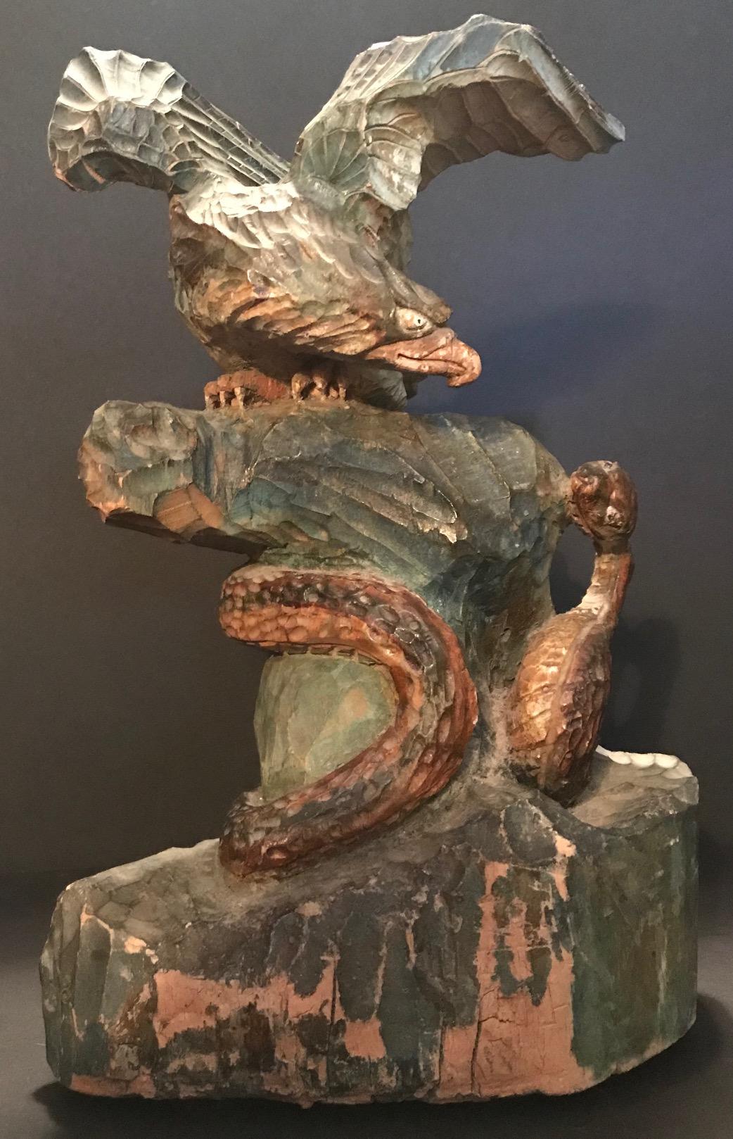 Our nation’s symbol is presented with its wings spread, perched on a rock ready to attack the aggressive serpent. This artistic and detailed wood carving displays a tremendous tension. The piece is polychrome painted in muted colors. There is some