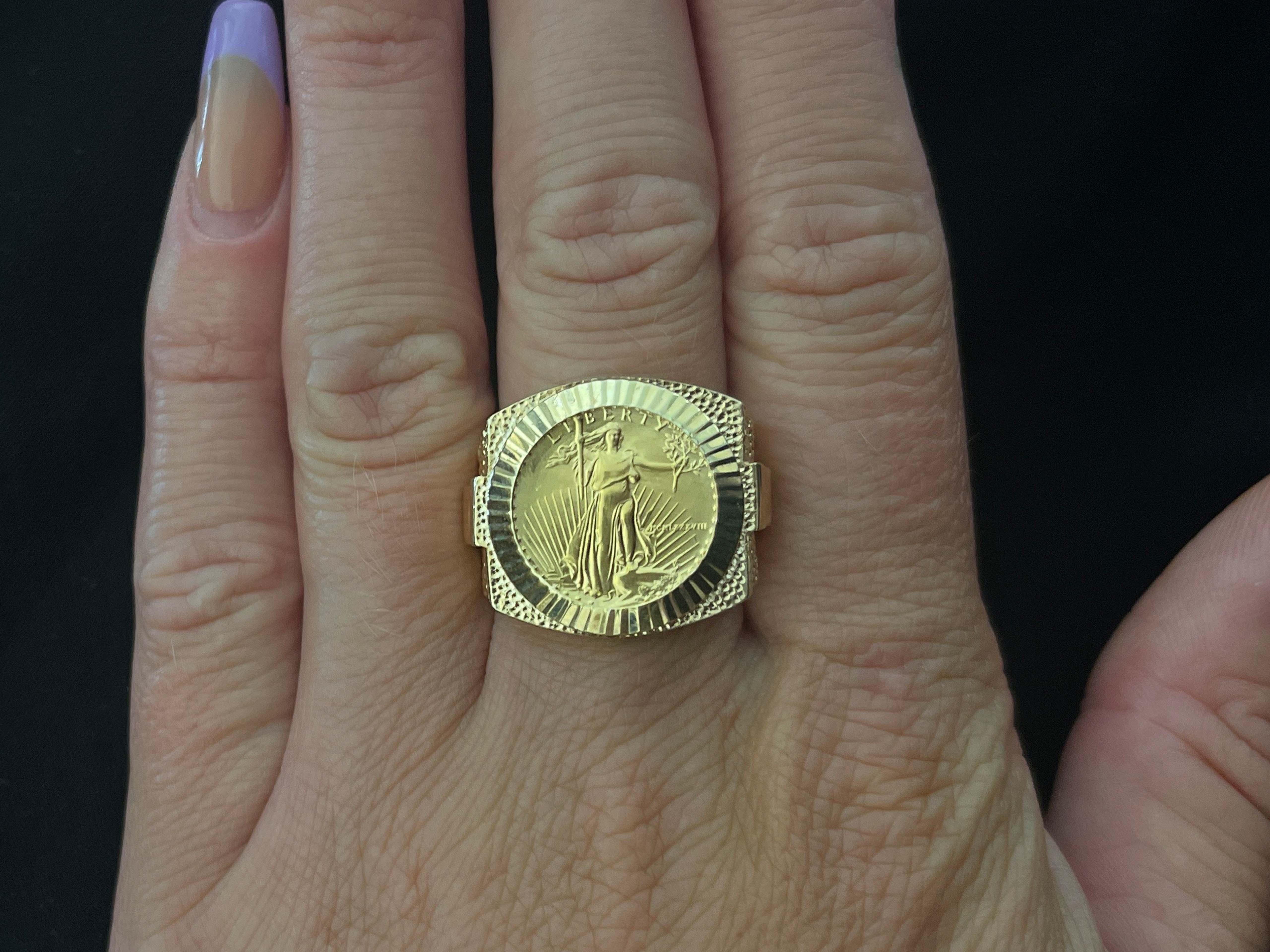 American Eagle Gold Coin Rolex Style Ring in 14k Yellow Gold. The ring contains one $5 American Eagle gold coin 0.10 troy ounce of pure gold. The coin is set in fluted bezel. The ring has a rolex design on the sides with a hammered and high polish