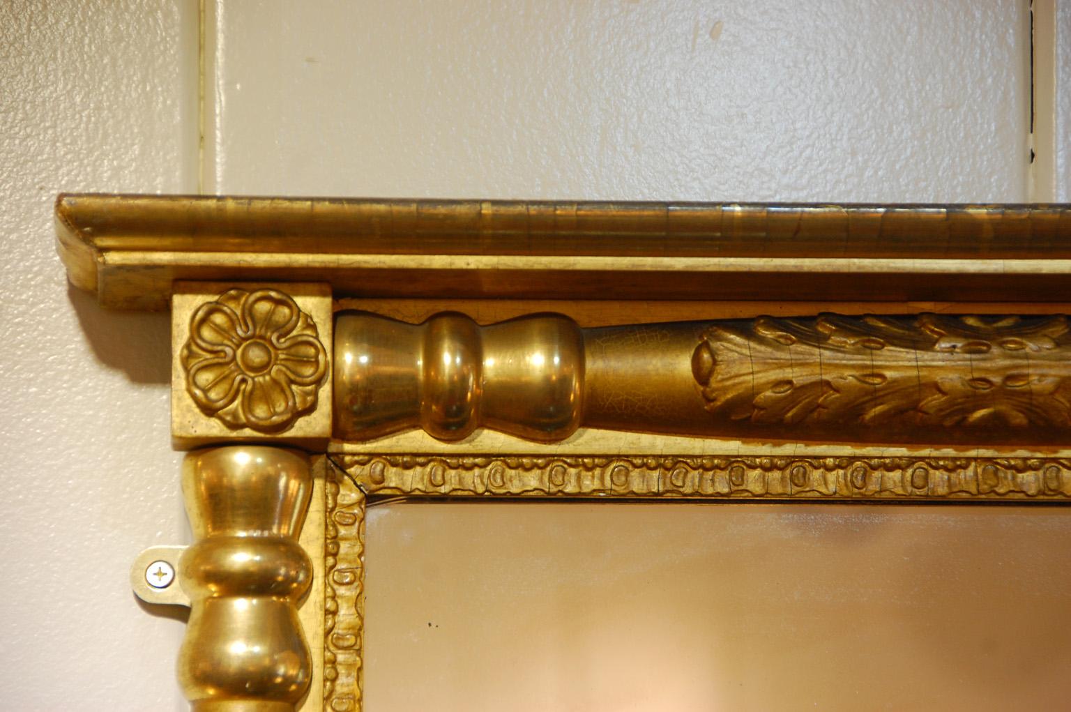 American early 19th century Federal period gold leaf overmantel mirror. This carved wooden split column mirror is enhanced by areas of brightly burnished gold which contrasts to the lightly burnished gold. The columns not only are turned but have