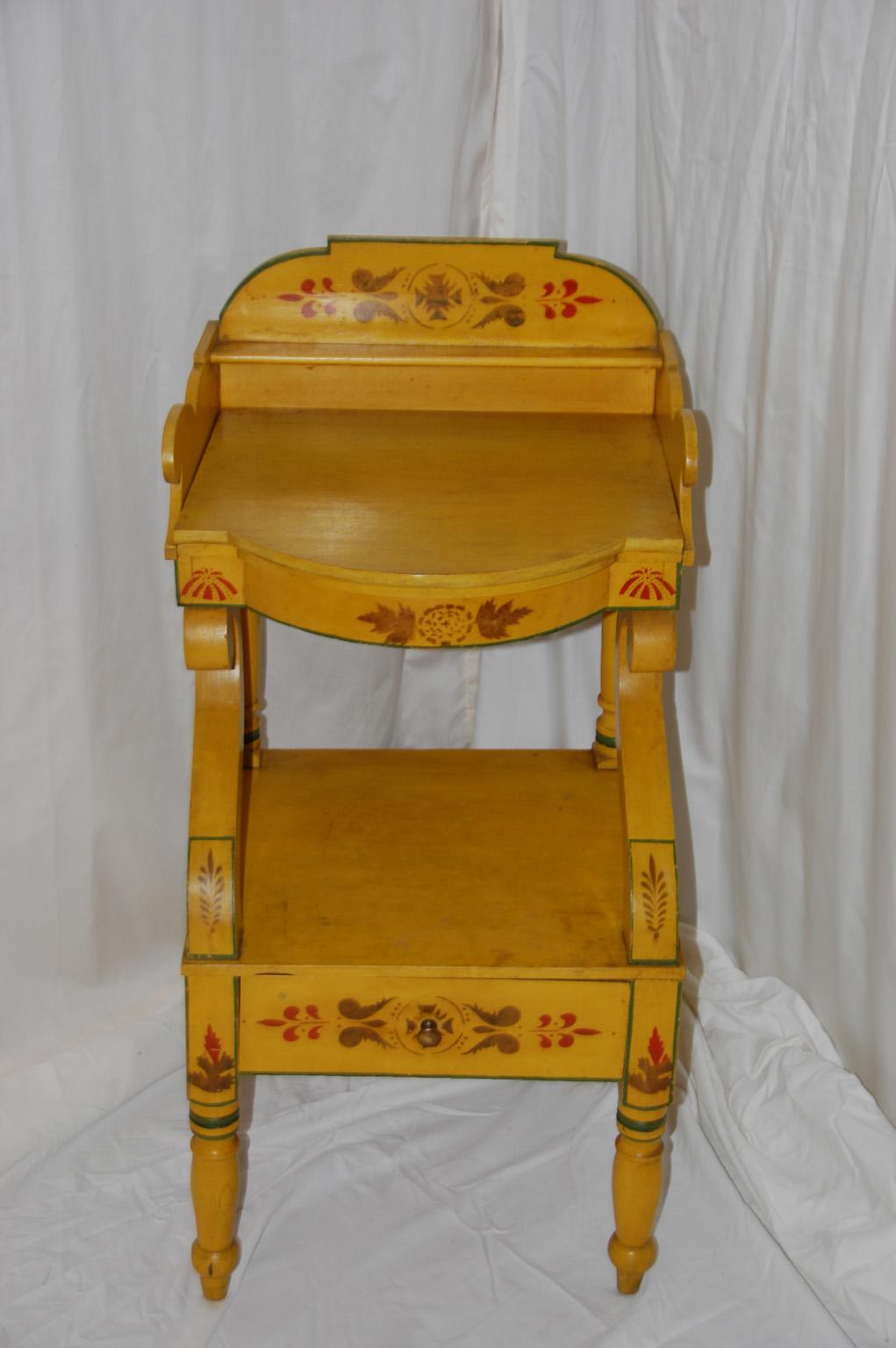 American New England painted and decorated bowfront pine washstand with removable painted cover. The cover conceals holes which held a washbowl and glasses or cups. Below the washbowl level is a shelf and drawer with neoclassical curving side