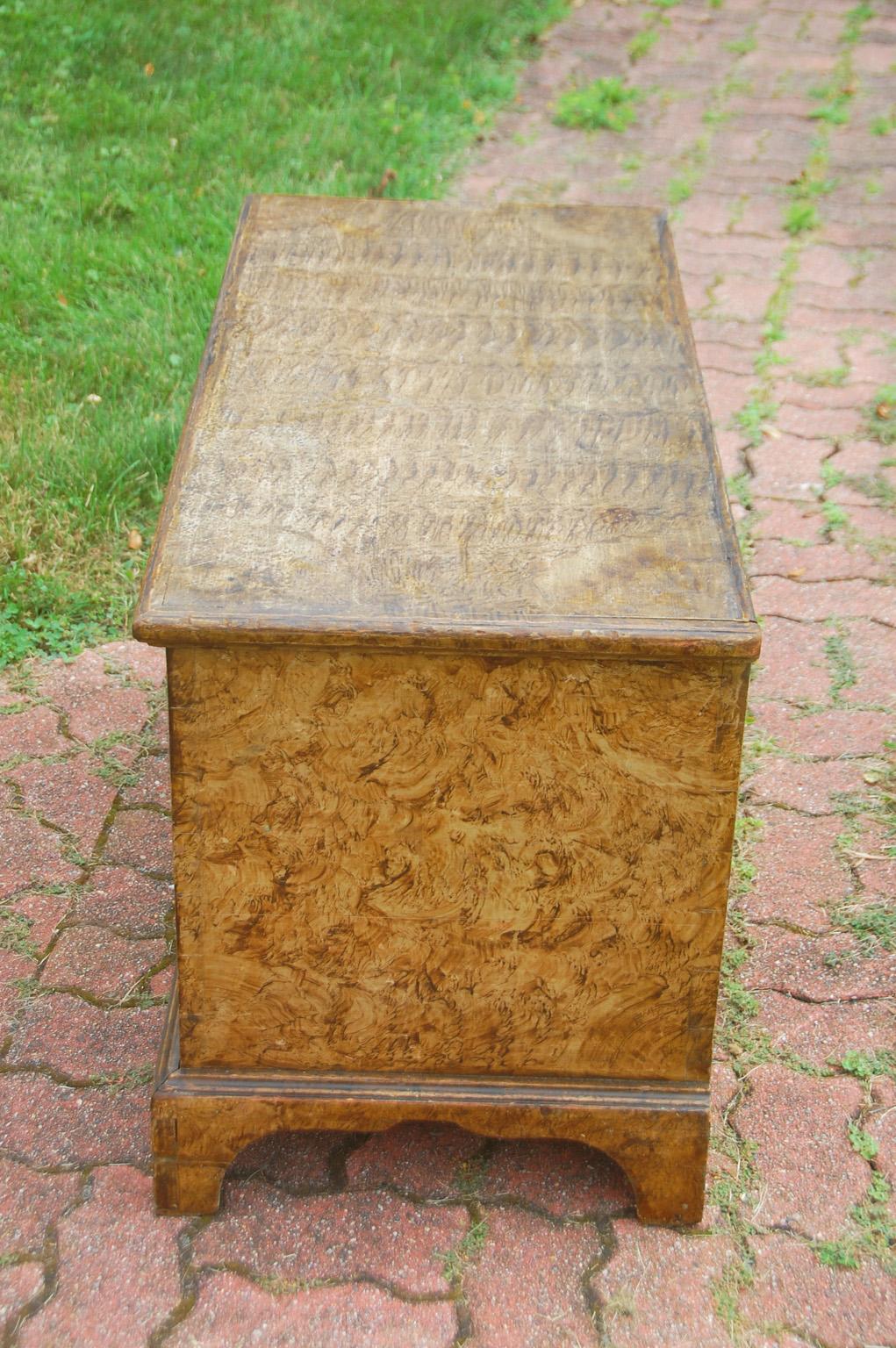 American early 19th century pine trunk with original sponge painted decoration, bracket base and interior ditty box. This trunk is made using the classic dovetailed construction of the time. It retains its original painted surface and has a good dry
