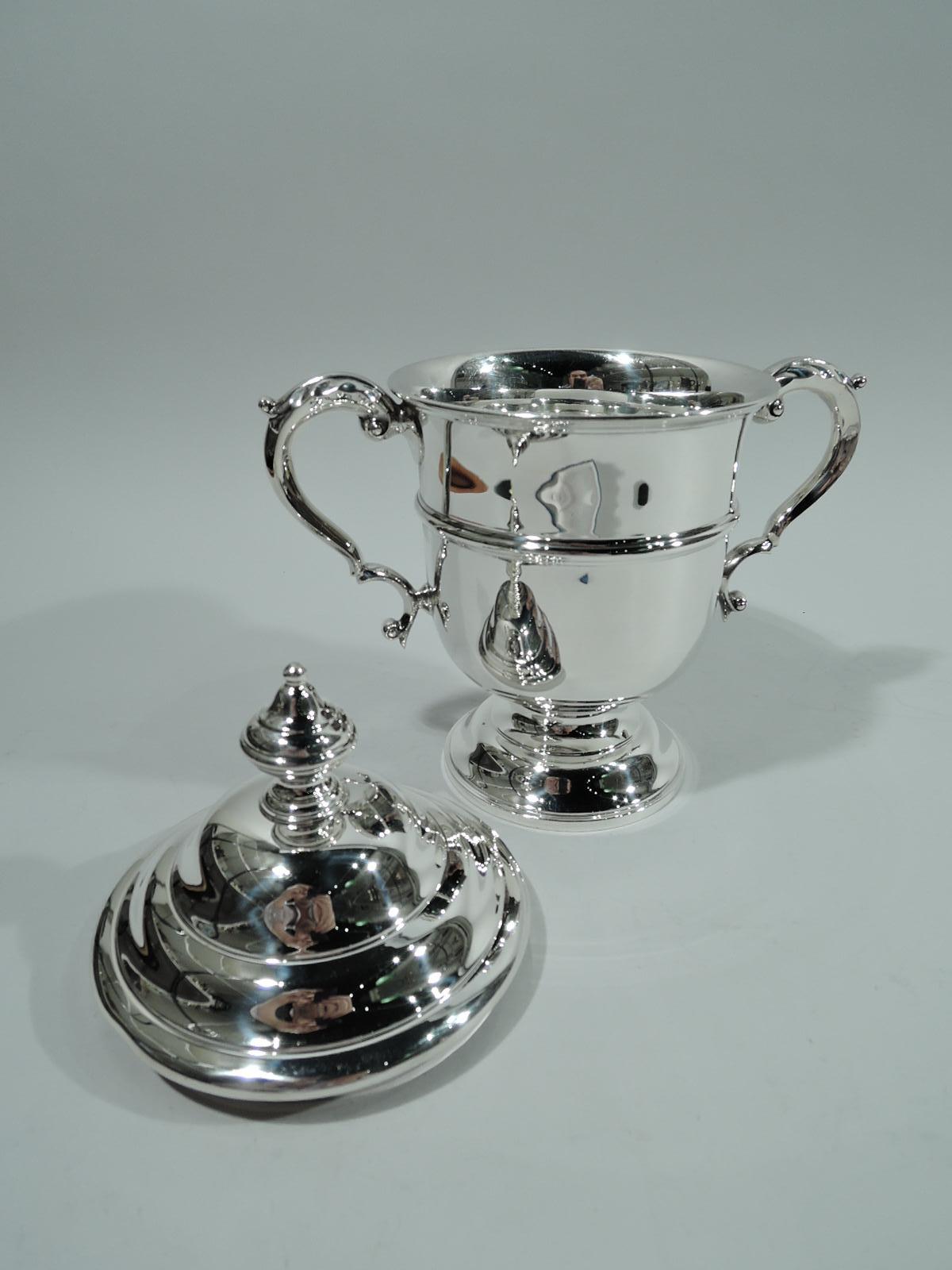 Edwardian classical sterling silver trophy cup. Made by Redlich in New York, ca 1920. Girdled urn with leaf-capped double-scroll side handles and domed foot. Cover double-domed with vasiform finial. Traditional form in a nice size with lots of room
