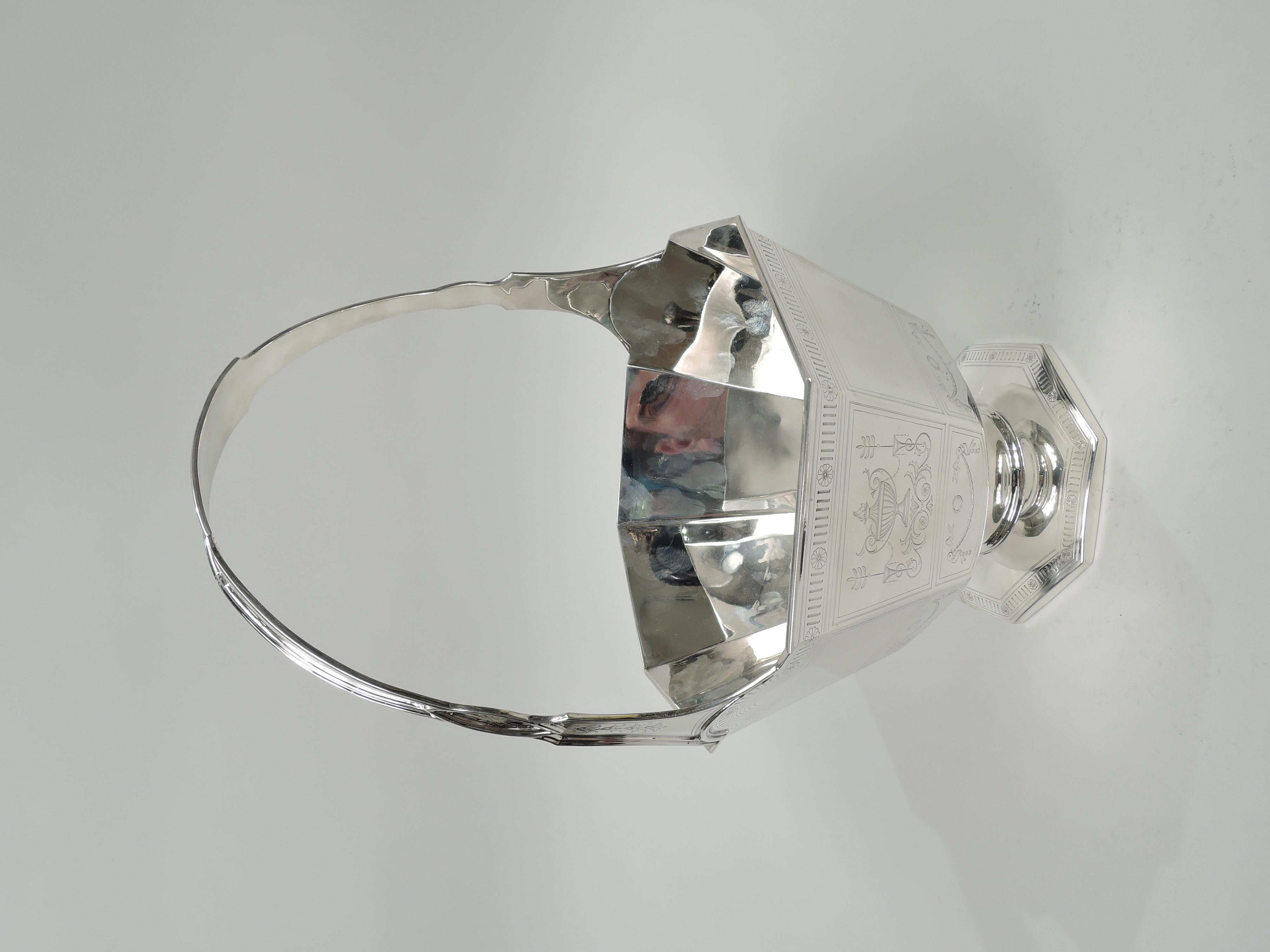 Edwardian Modern Regency sterling silver basket. Made by the Sweetser Co. in New York, ca 1910. Faceted octagonal bowl with straight and tapering sides on spool support mounted to raised and faceted octagonal foot; fixed curvilinear handle. Engraved
